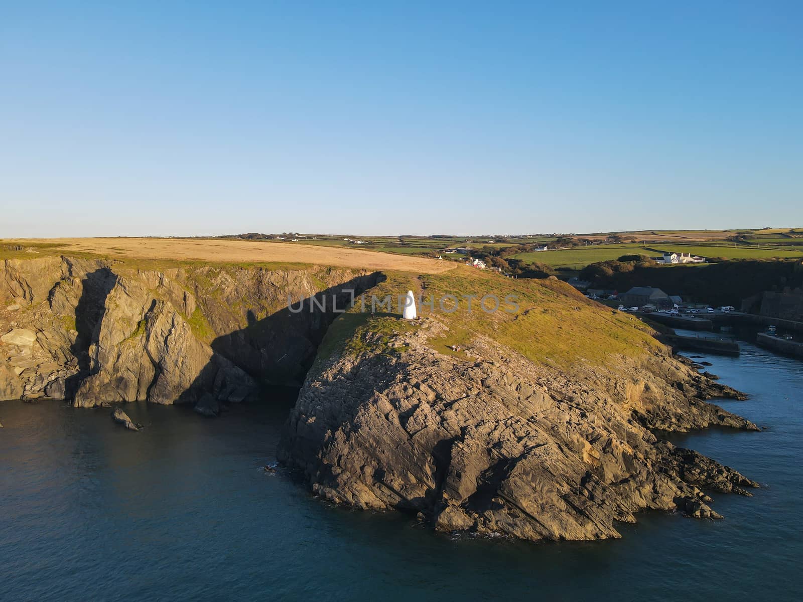 The Entrance From The Sea To Porthgain Harbour in Pembrokeshire, Wales, UK is Marked By White Pillars High On The Cliffs Of The Coast