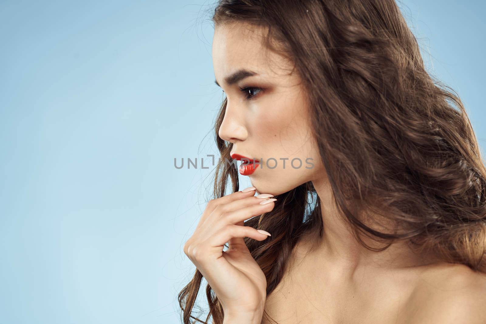 Beautiful woman naked shoulders hairstyle care bright makeup blue background. High quality photo