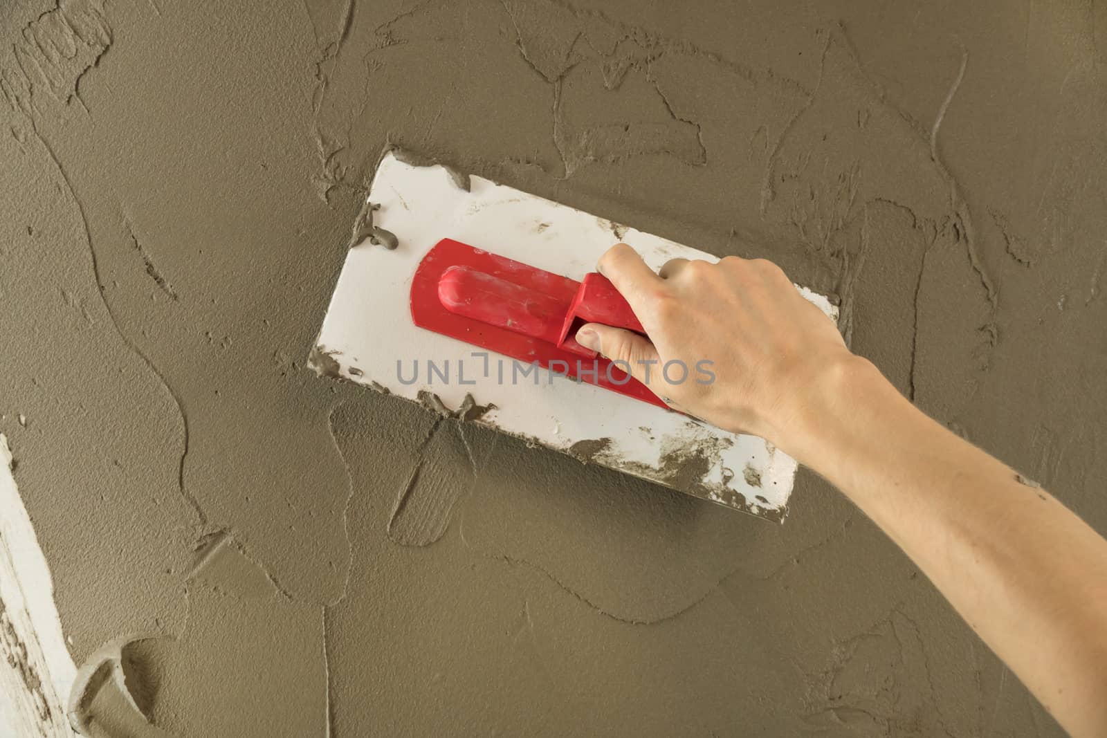 A worker plasters the wall with a spatula and applies a cement m by YevgeniySam