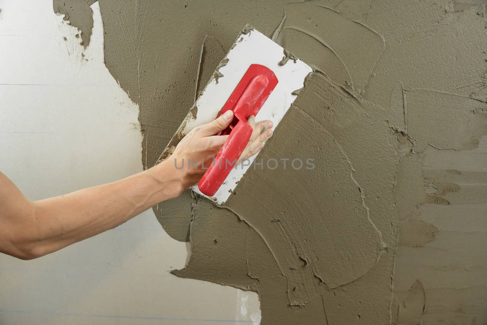 A worker plasters the wall with a spatula and applies a cement m by YevgeniySam