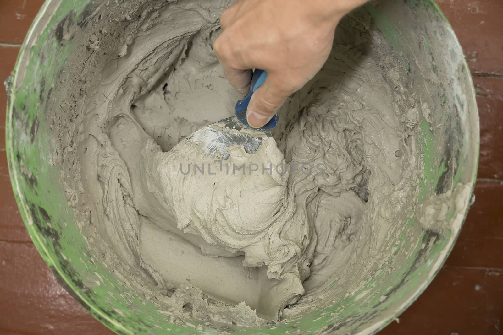 A worker uses a spatula to get a solution of the cement mixture. by YevgeniySam