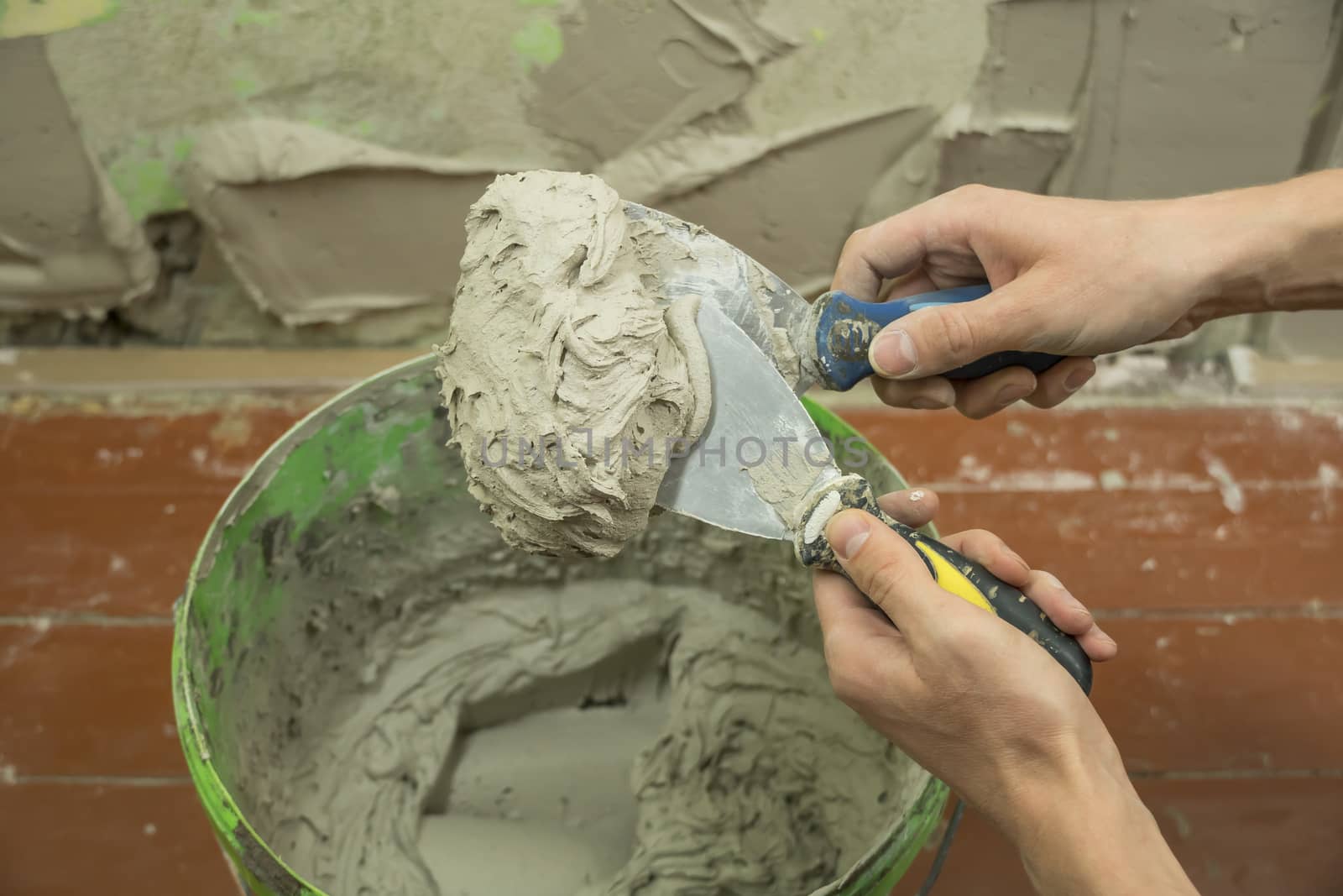 A worker uses a spatula to get a solution of the cement mixture. by YevgeniySam