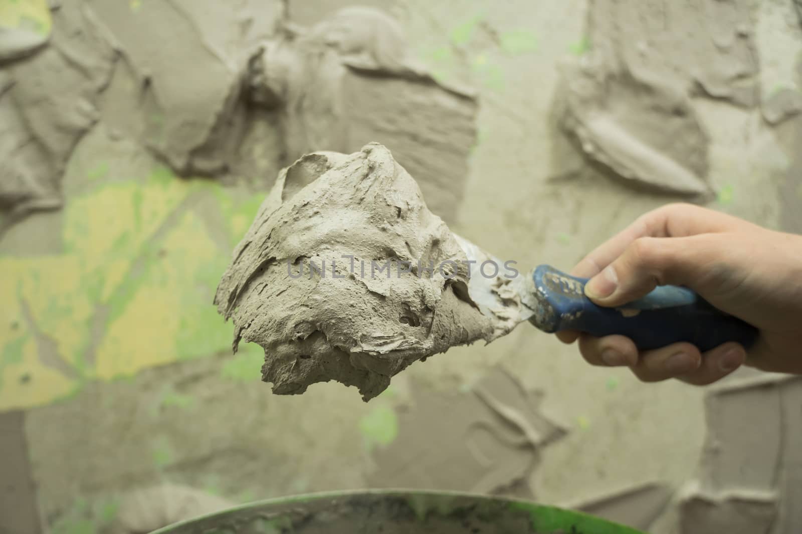 A worker uses a spatula to get a solution of the cement mixture. by YevgeniySam