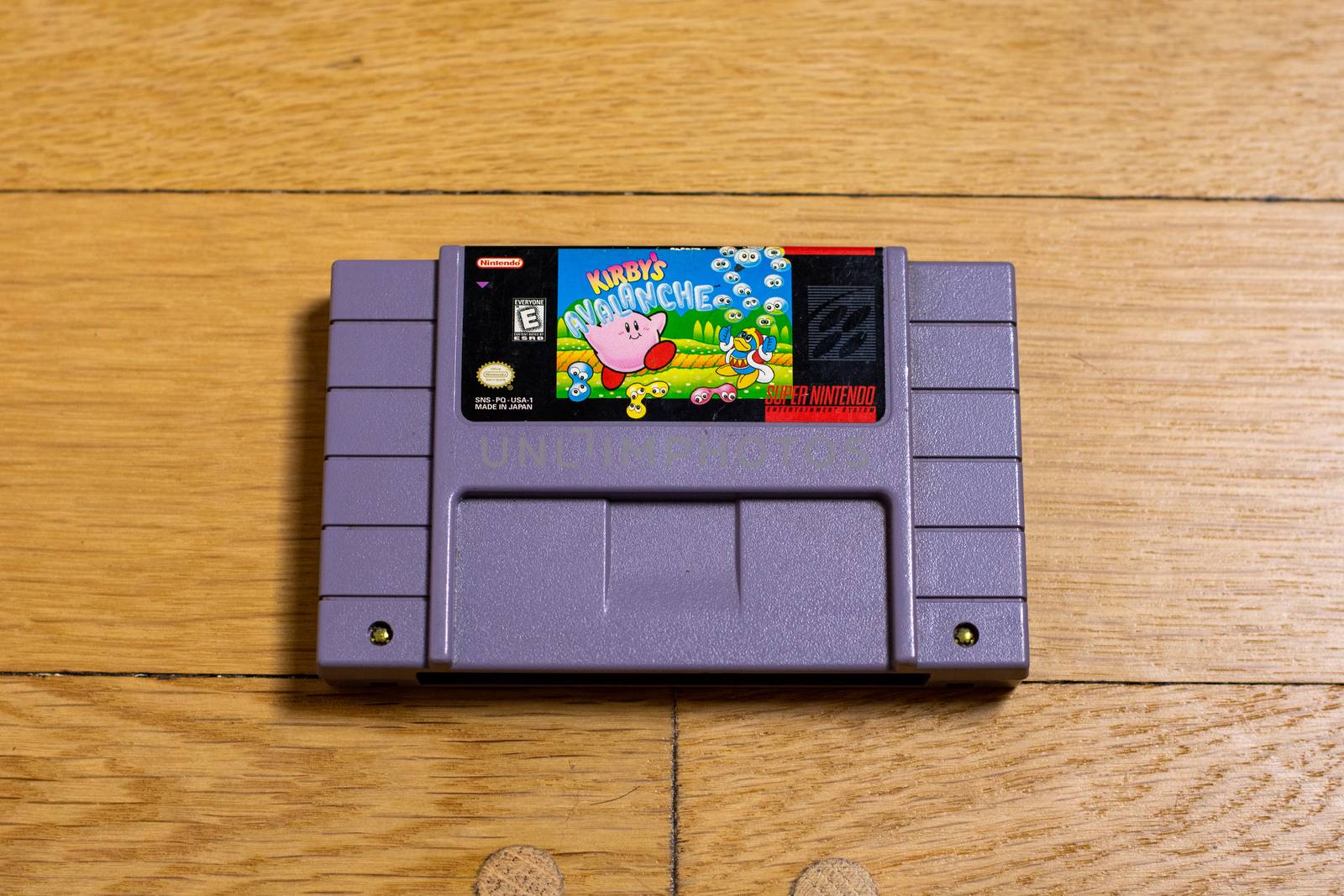 A Kirby's Avalanche Cartridge for the Super Nintendo Entertainment System on a wood floor.