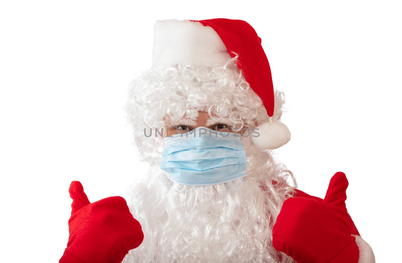 View of a man wearing a Santa Claus costume and medical mask with his thumbs up, isolated on white background. Man looks straight in the camera and is stressed. New normal, pandemic holiday concepts by DamantisZ