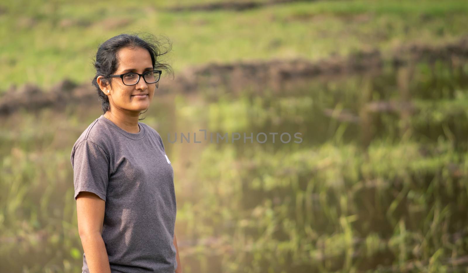 Southern Province / Sri Lanka - 10 24 2020: Young beautiful innocent female pose for the camera in front of the rice paddy field in a rural village.