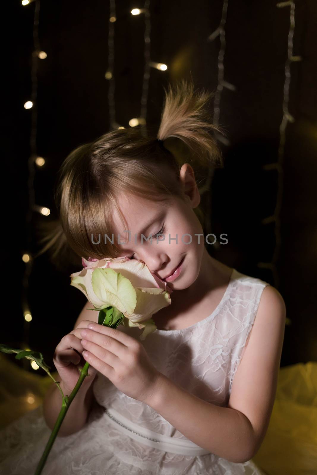 Young adorable pretty girl with rose from her father over dark background with garlands bokeh