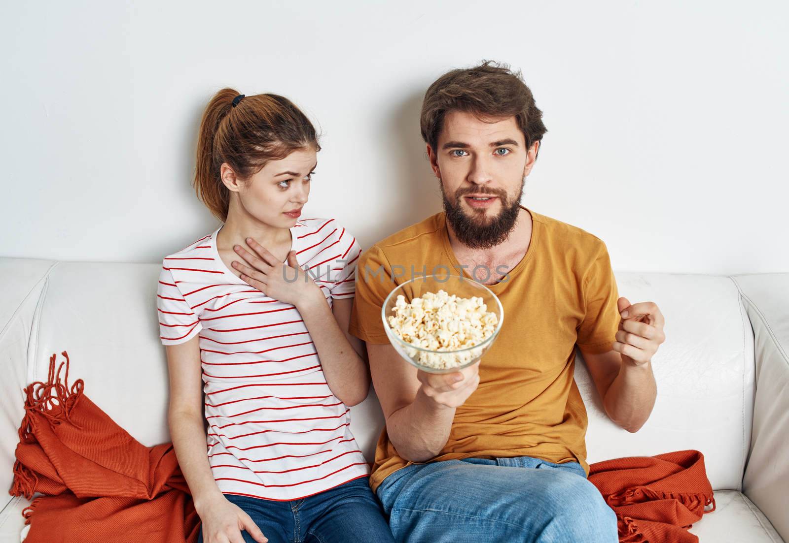 married couple on the couch popcorn watching tv indoors man woman. High quality photo