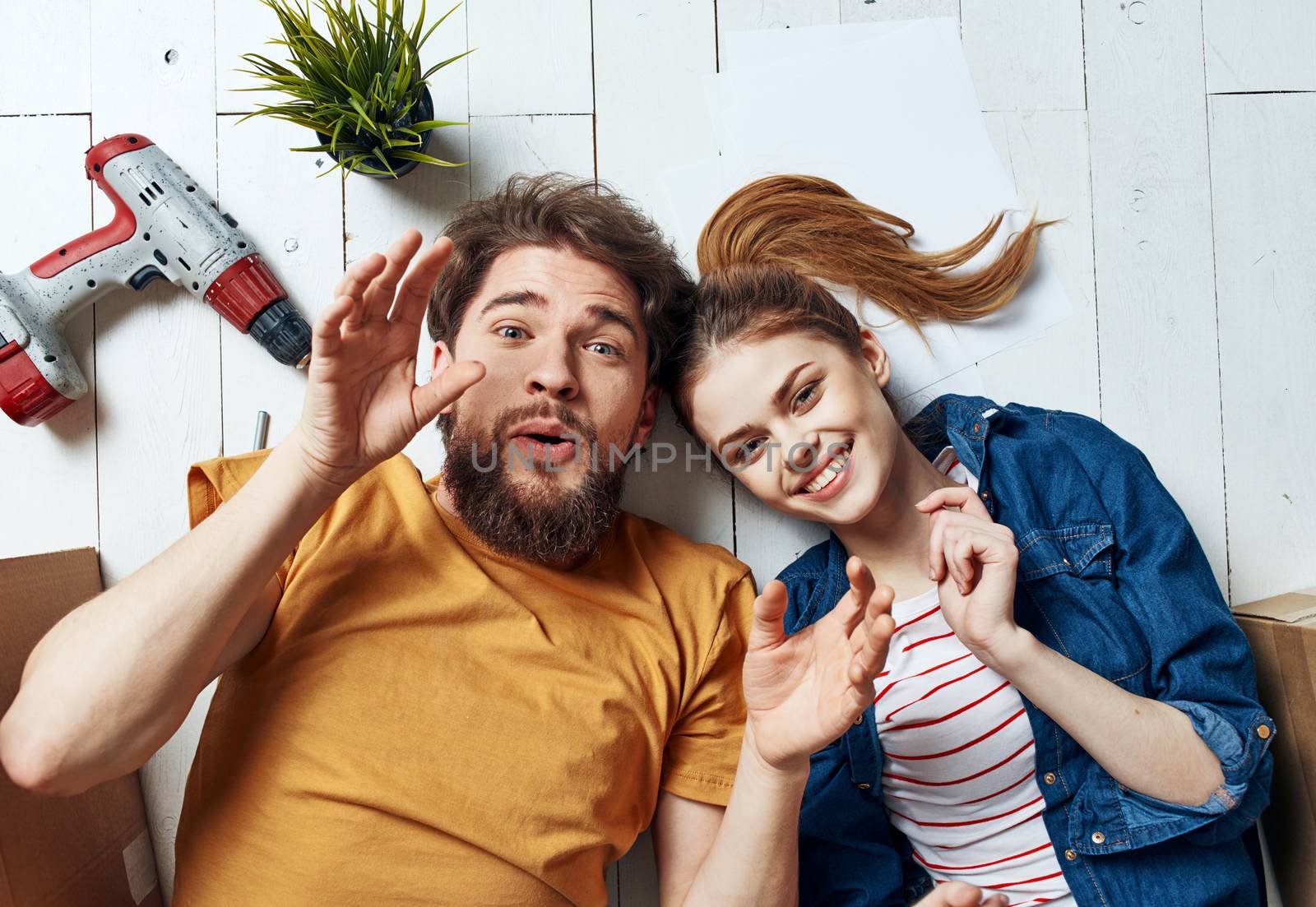 man and woman with boxes around lie on the floor moving flower in a pot repair work. High quality photo