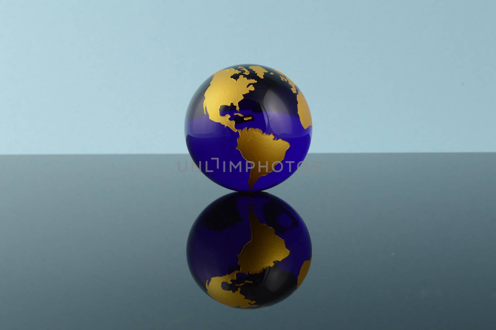 A crystal blue globe of the Earth over a reflective background.