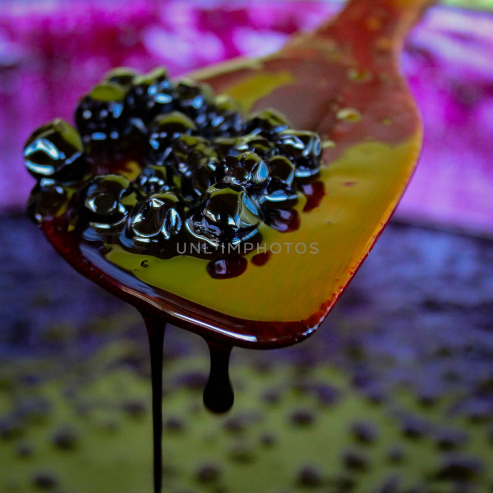 A wooden cooking spoon with chokeberry berries on it during the process of making chokeberry jam. by mahirrov