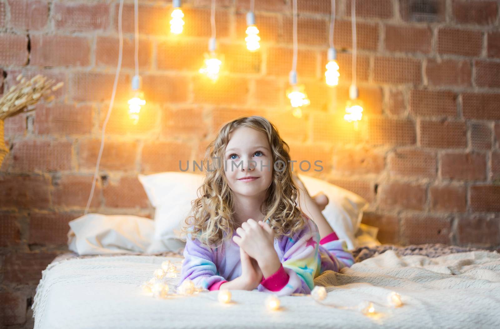 .A girl in pajamas lies on the bed waiting for a christmas present on the background of garlands