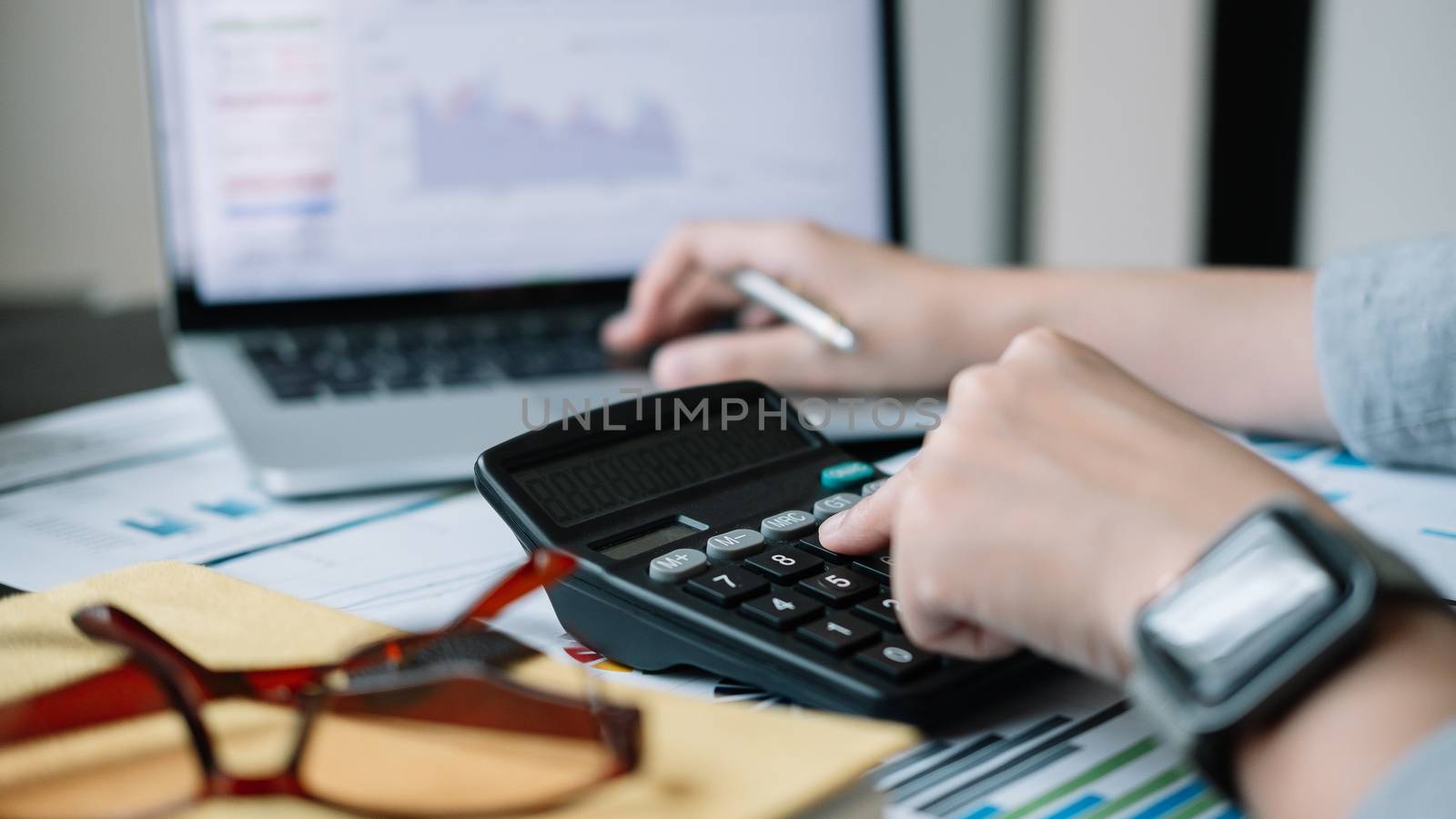 accountant working on desk using calculator for calculate finance report at home.