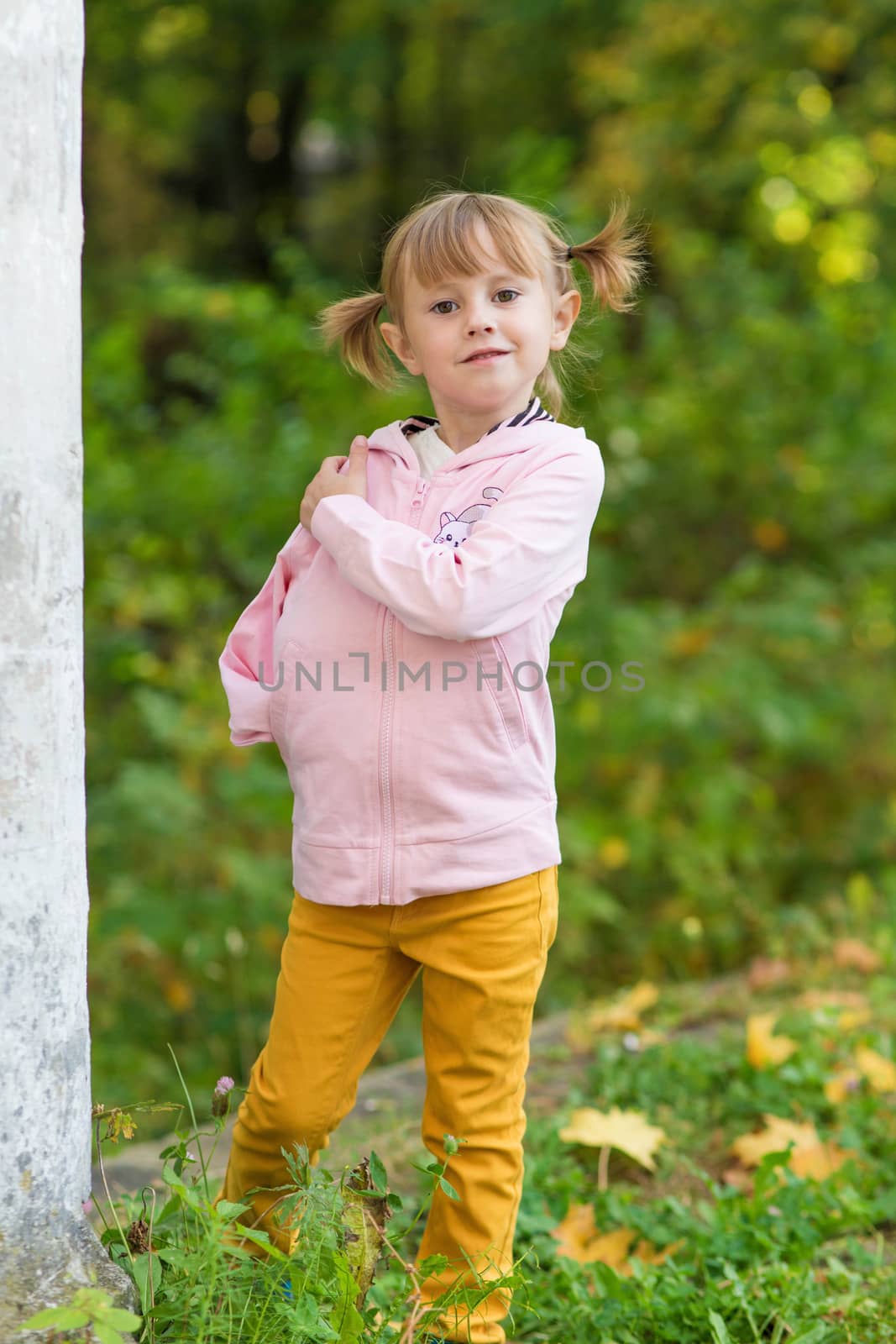 .A girl with a broken arm stands near a column in an old park on an autumn walk