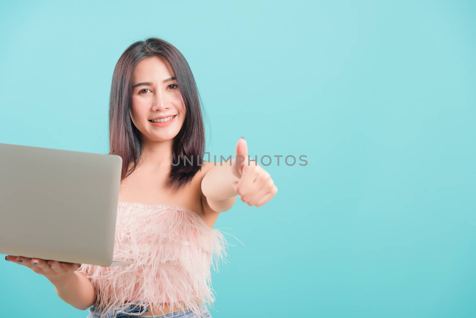 woman standing smile her  holding laptop computer show finger th by Sorapop