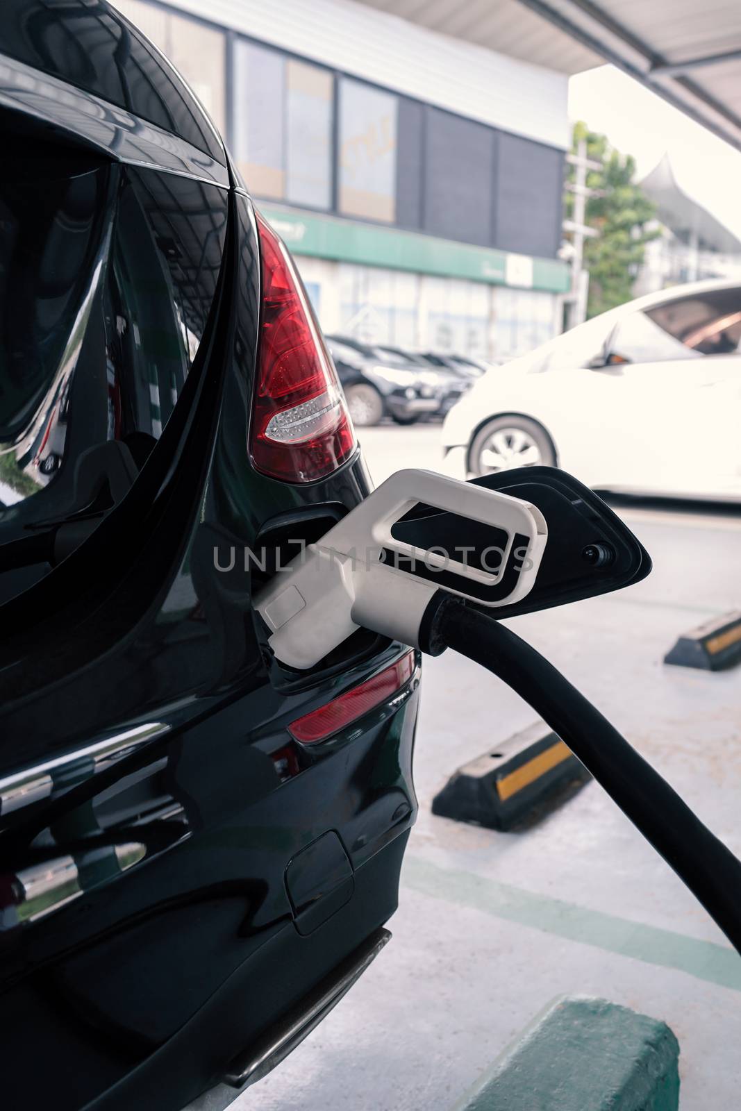 power supply connects to plug-in electric vehicle or electric car at charging station by happycreator