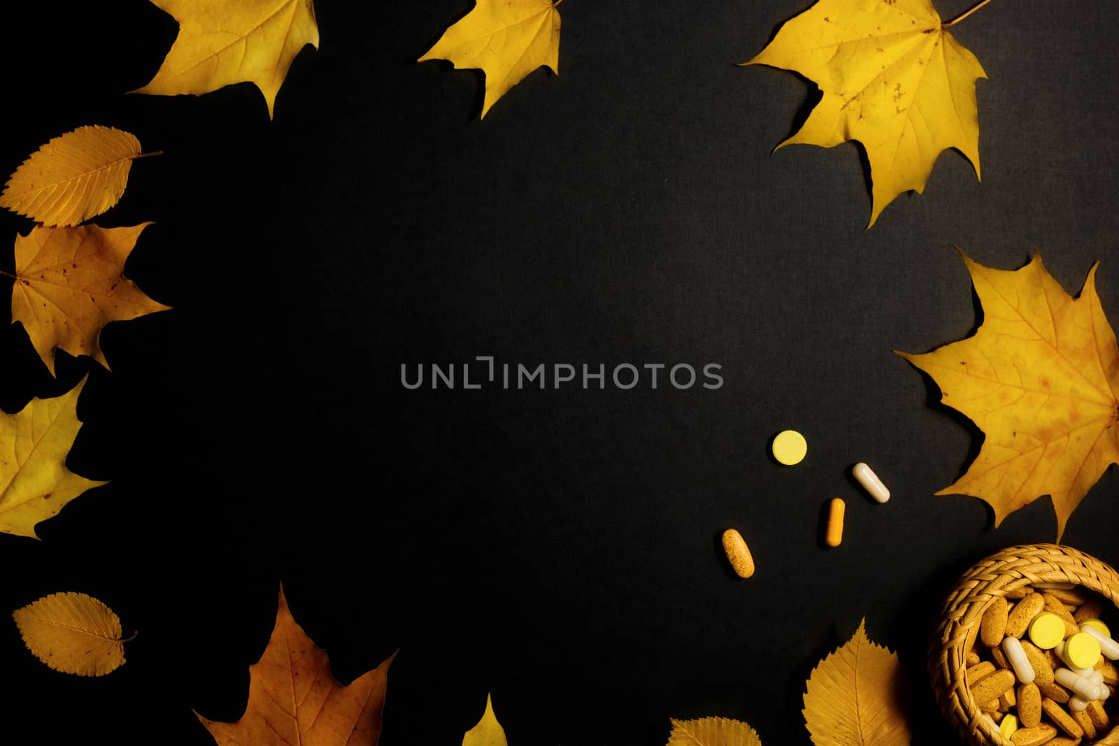 Autumn fallen leaves and medicines on black background