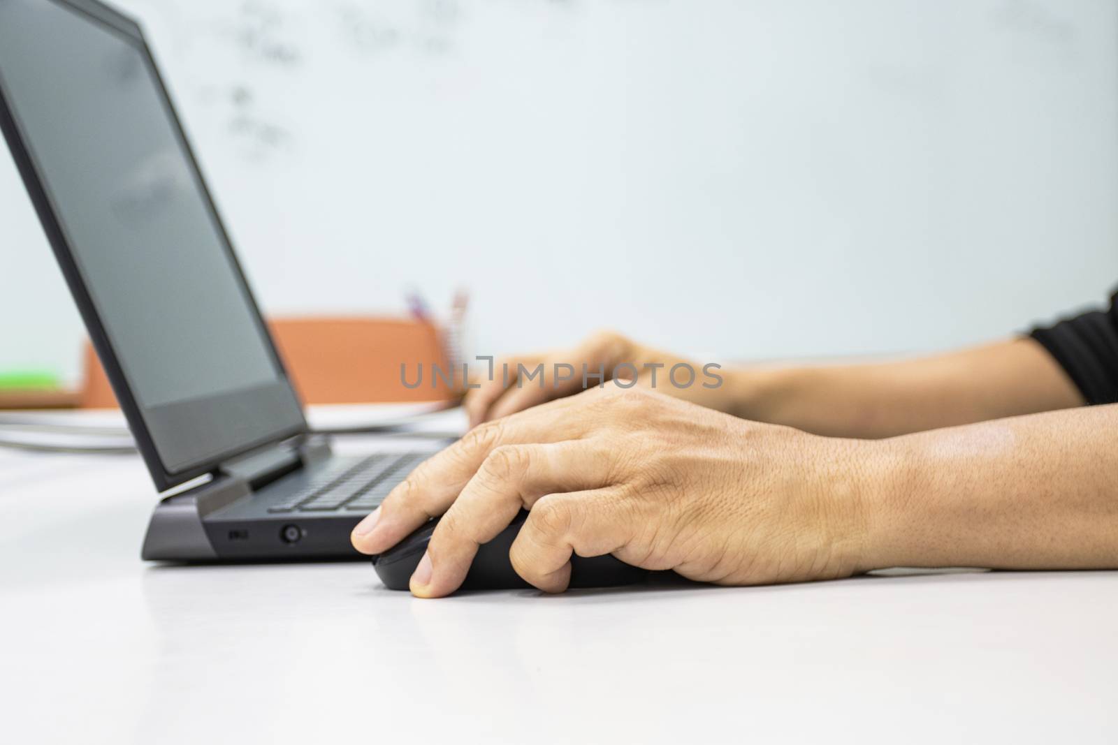 A man sitting using a laptop with hand to hold a mouse show office syndrome concept with weire wrist from hold mouse use 