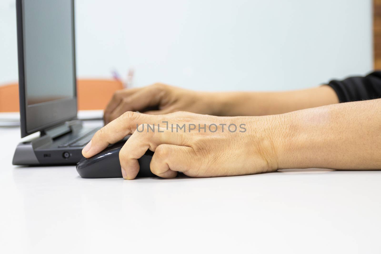 A man sitting using a laptop with hand to hold a mouse show office syndrome concept with weire wrist from hold mouse use 
