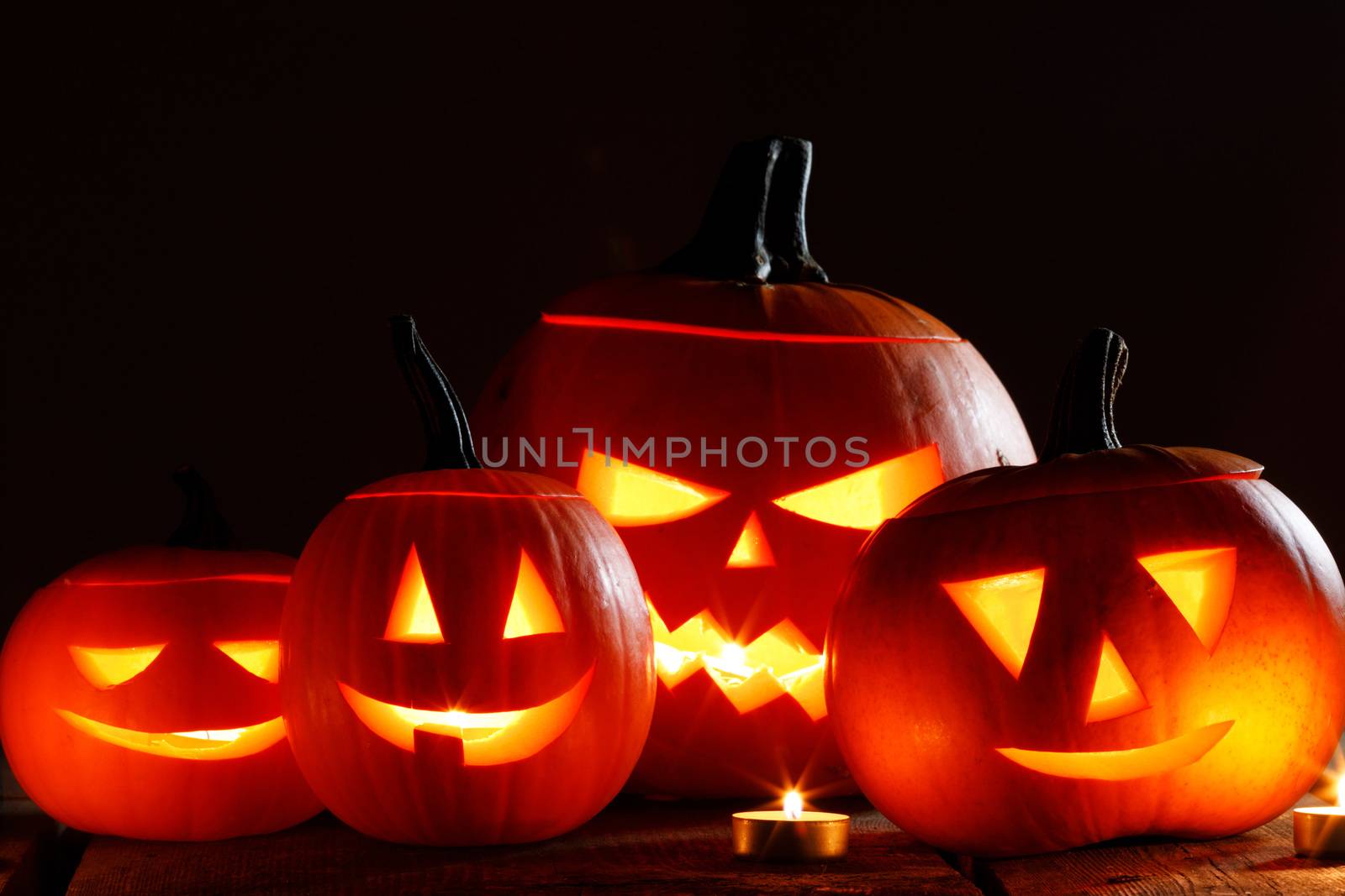 Halloween pumpkin head lanterns and burning candles on wooden background isolated on black