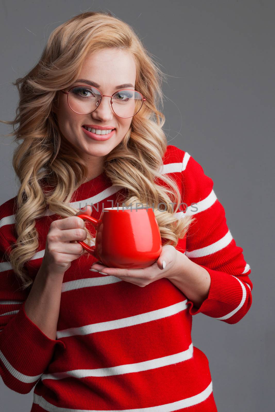Beautiful blonde woman in glasses holding red cup of drink Christmas Valentines day concept