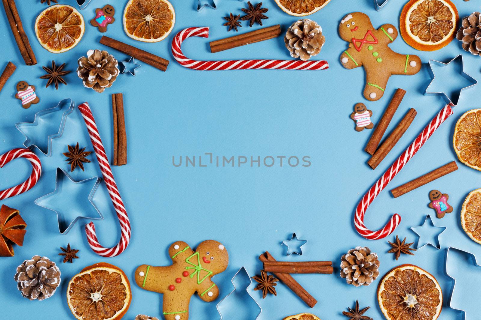 Christmas food frame. Gingerbread cookies, spices and decorations on blue background with copy space