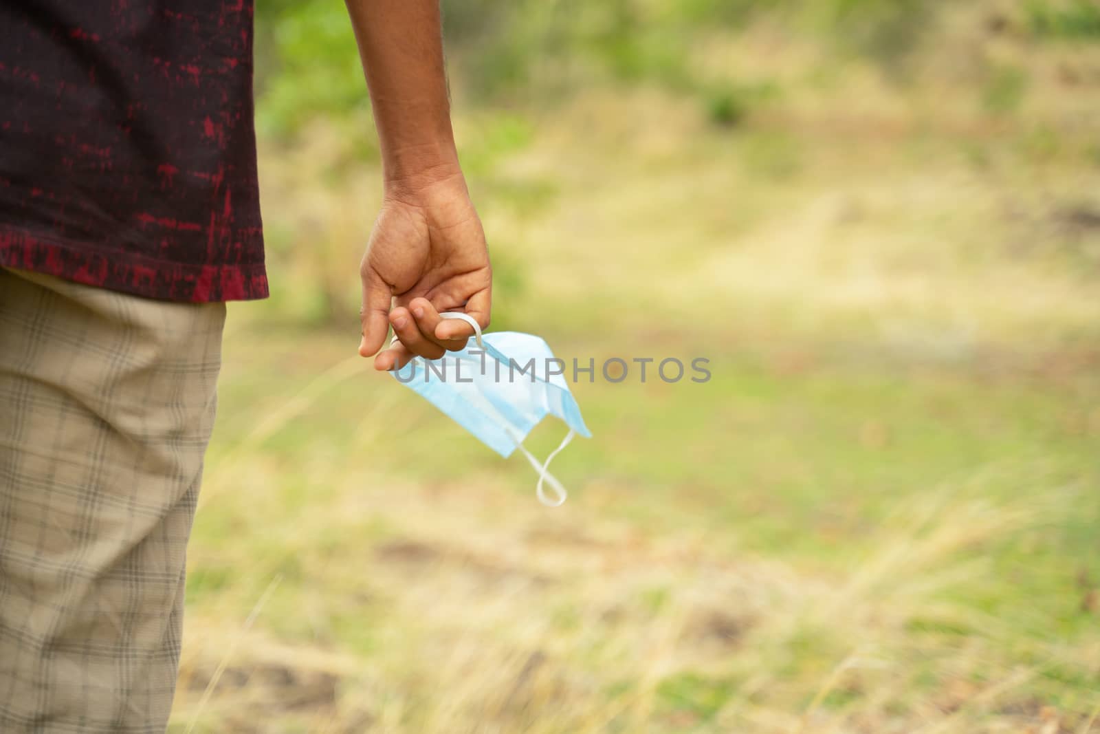 Closeup of hands holding medical mask with copy space - concept of removing mask to feel nature during coronavirus or covid-19 pandemic on top of mountain