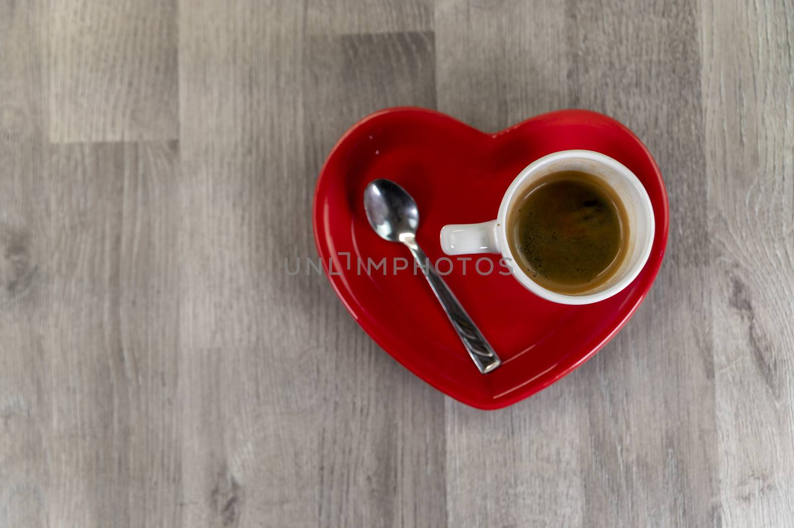 a cup of coffee with a heart-shaped saucer and a teaspoon
