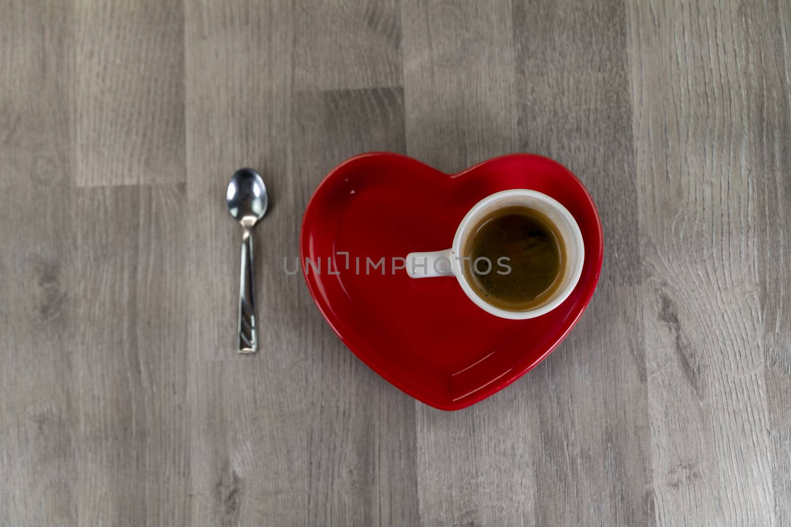 a cup of coffee with a heart-shaped saucer and a teaspoon