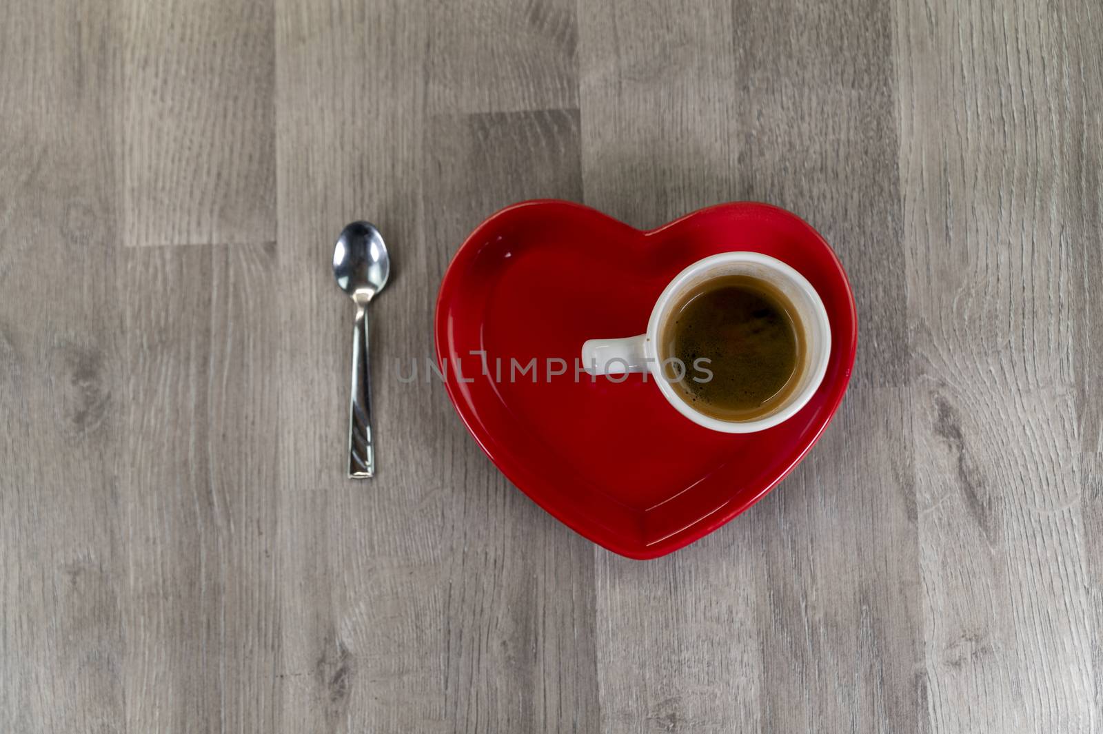 a cup of coffee with a heart-shaped saucer and a teaspoon