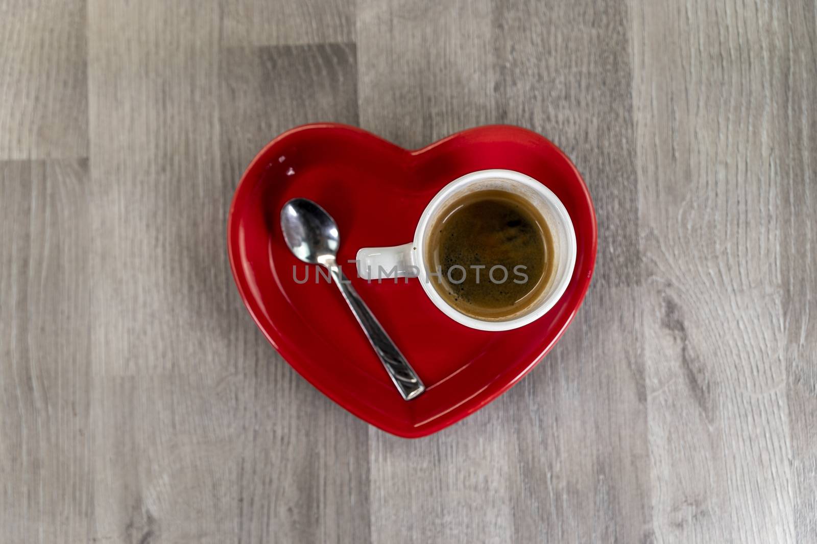 a cup of coffee with a heart-shaped saucer and a teaspoon