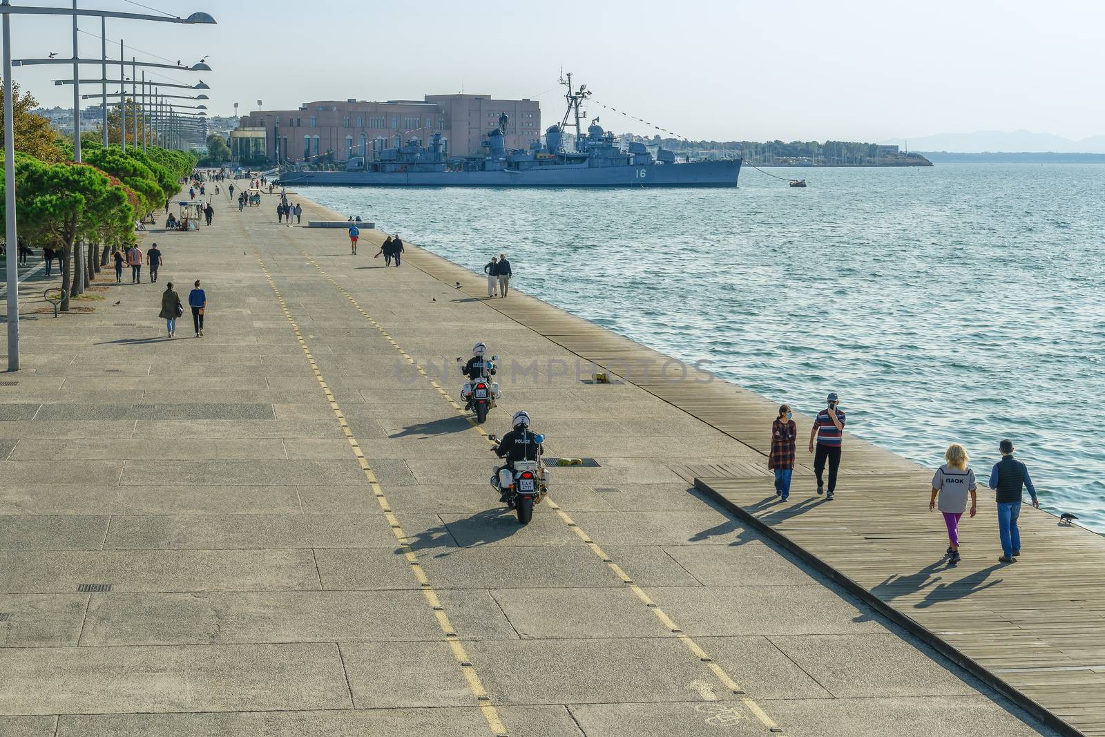 Unidentified persons with face protection walk on the pedestrian area of the city waterfront in Thessaloniki, Greece.