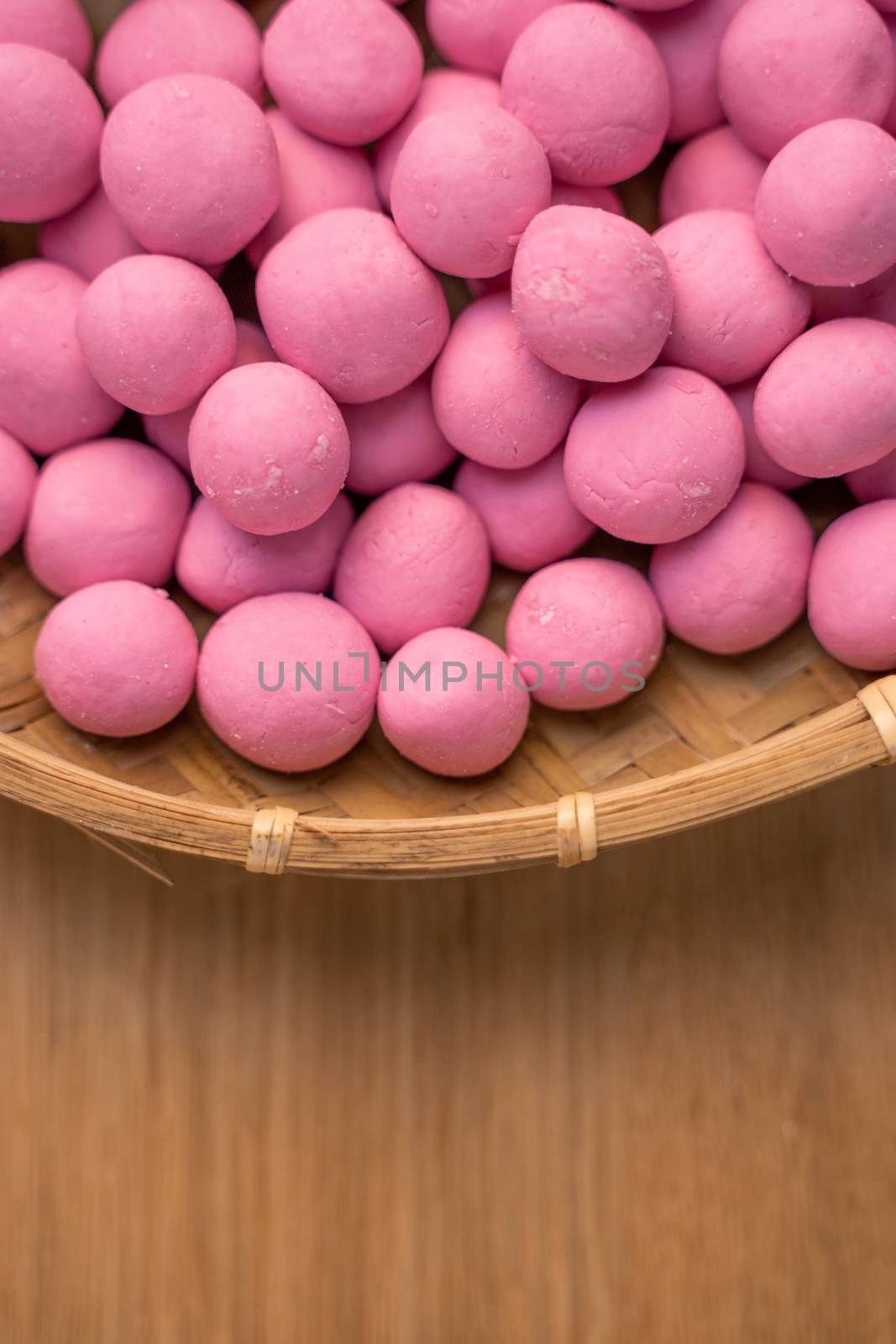 Raw little red and white tangyuan in a sieve over wooden table, concept of preparing food for winter solstice festival.