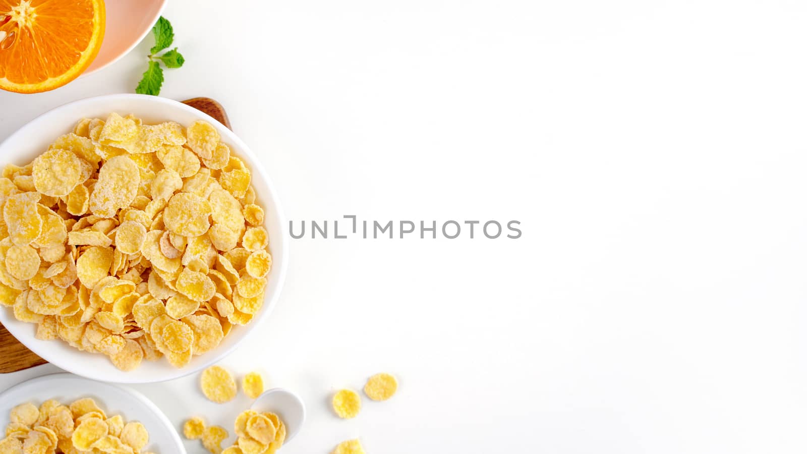 Top view of corn flakes bowl sweeties with milk and orange on white background, flat lay overhead layout, fresh and healthy breakfast design concept.