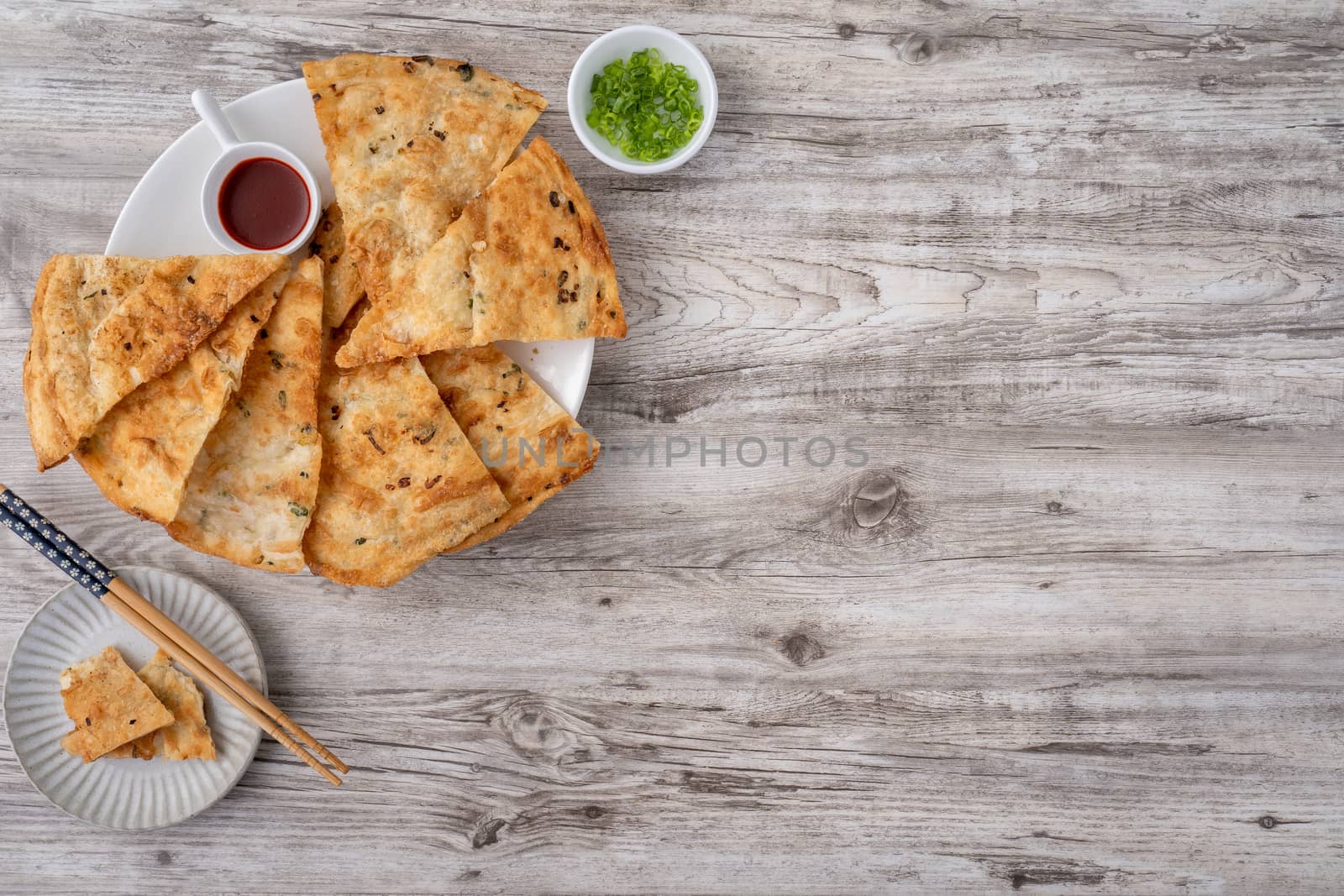 Taiwanese food - delicious flaky scallion pie pancakes on bright wooden table background, traditional snack in Taiwan, top view.