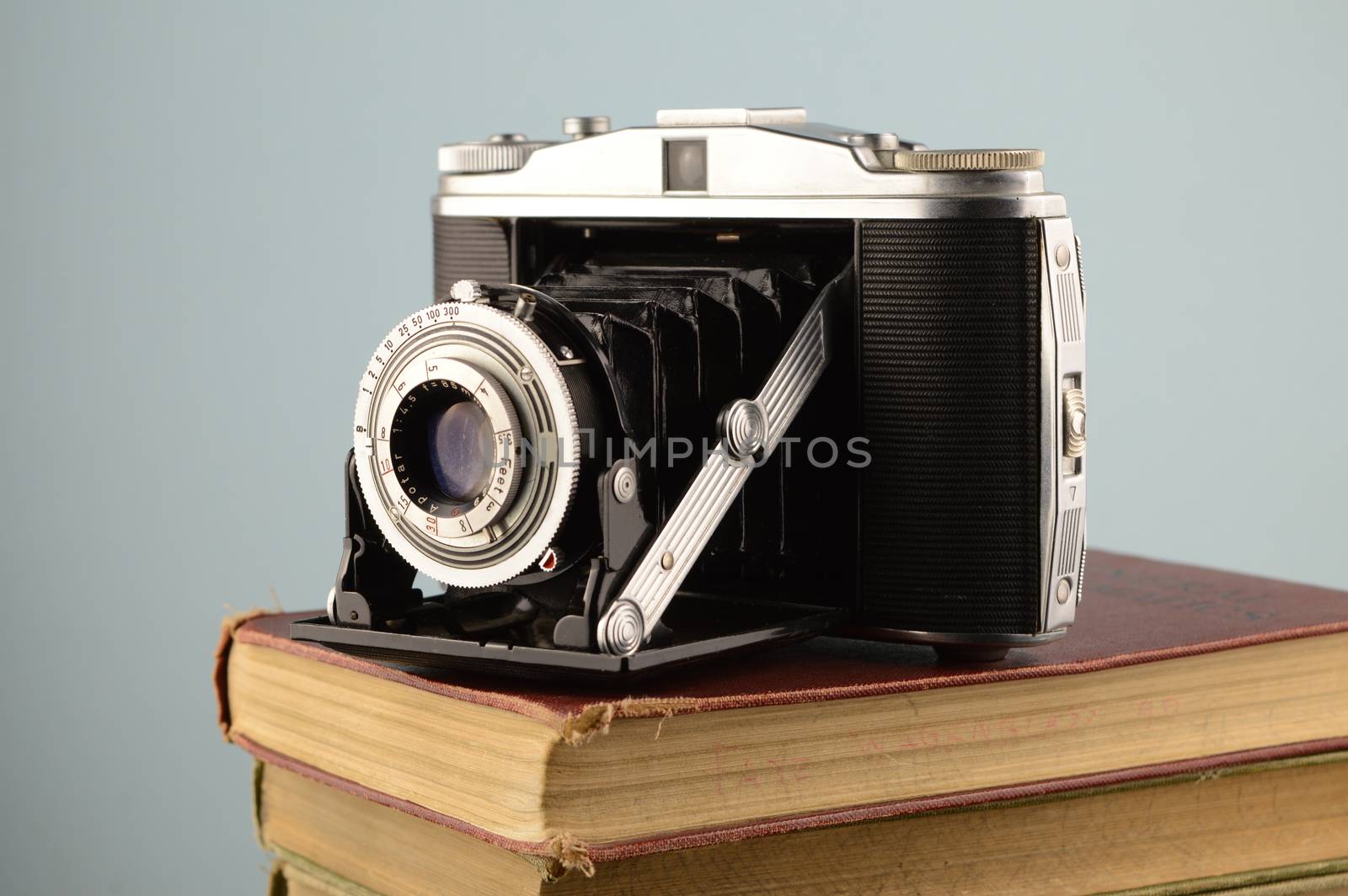 A vintage camera resting on a stack of old books.