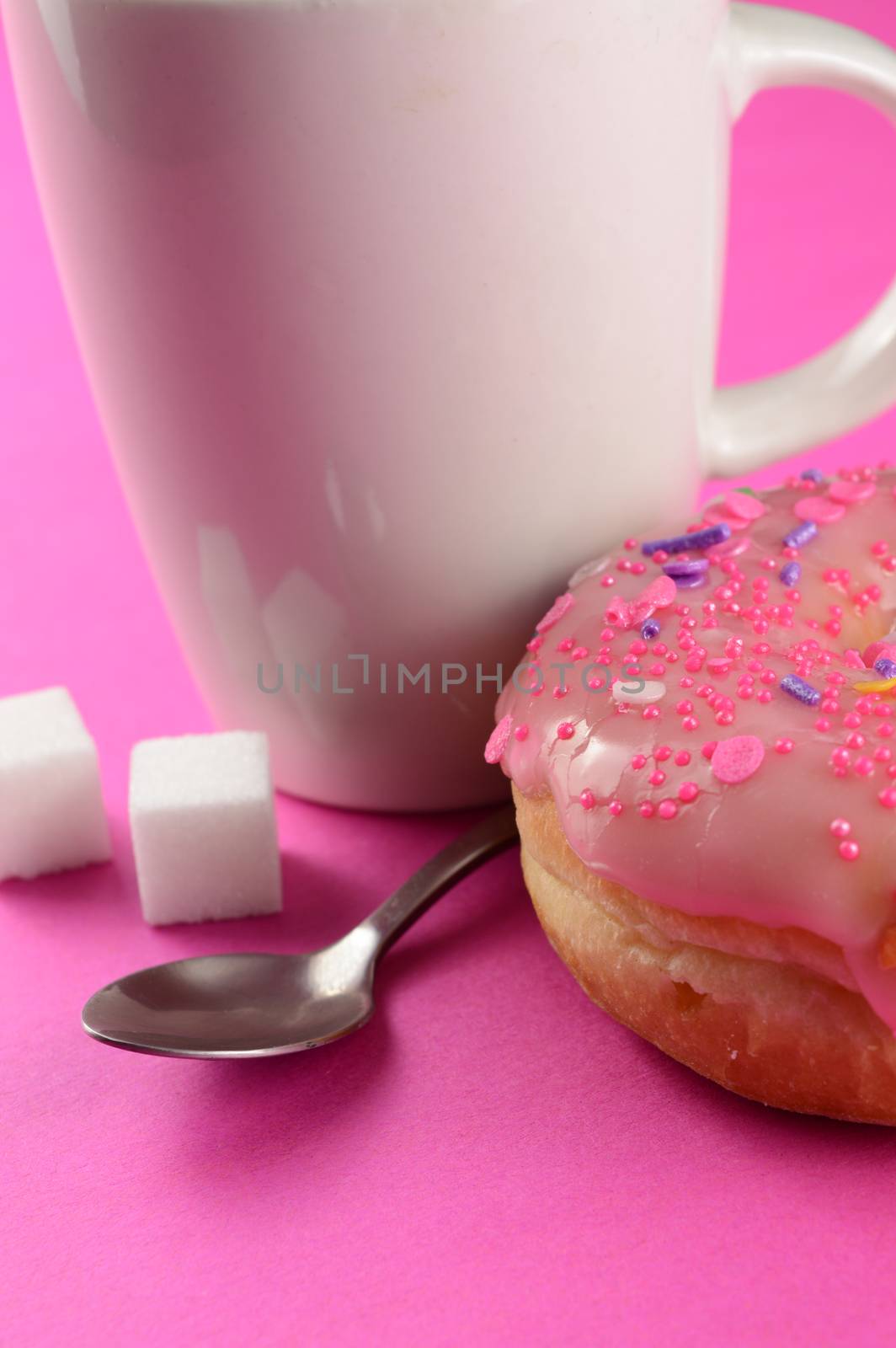 A vetical format closeup of hot pink coffee and donuts.