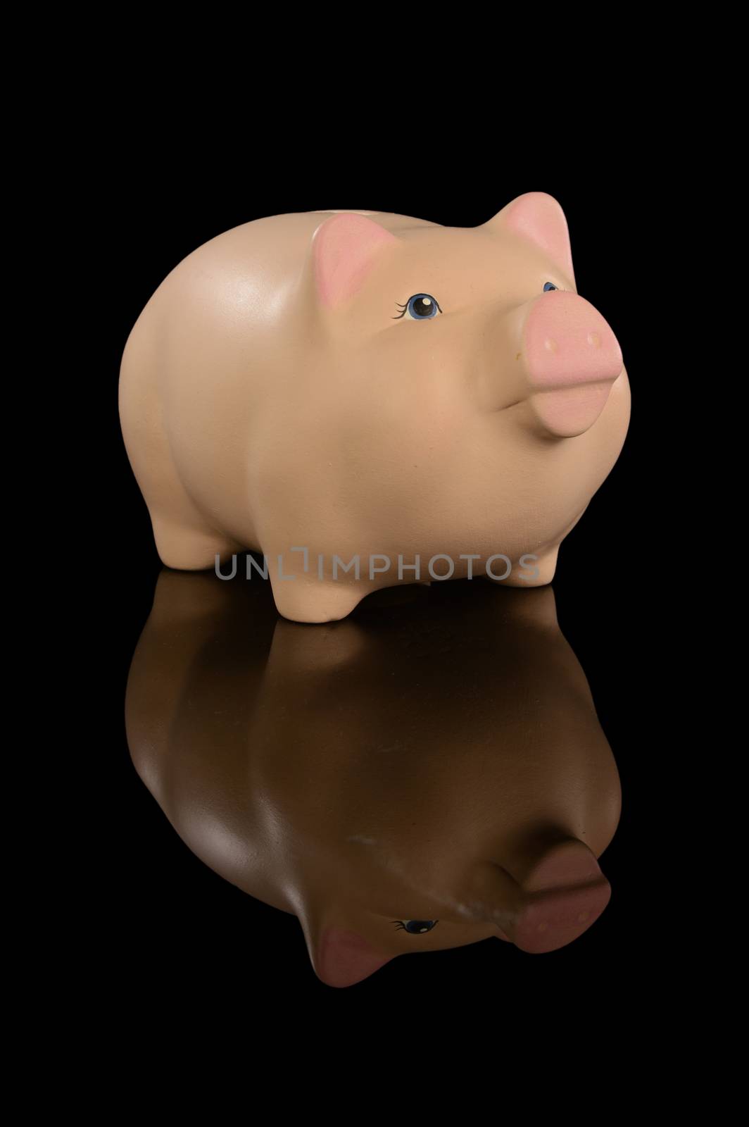 An isolated over a black reflective background image of a ceramic coin piggy bank to illustrate financial concepts.