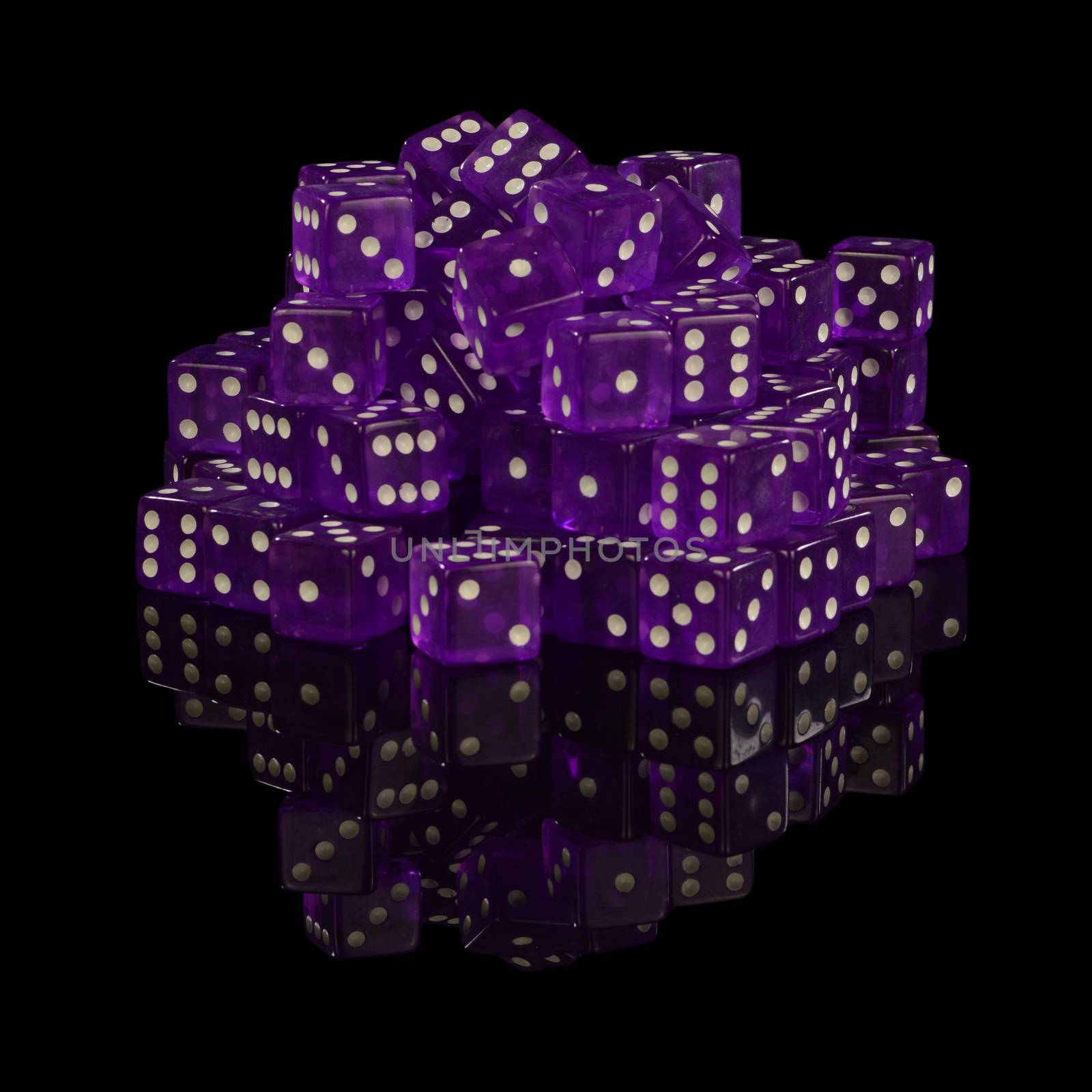 A heaping pile of new unused casino grade dice with a black reflective surface background.