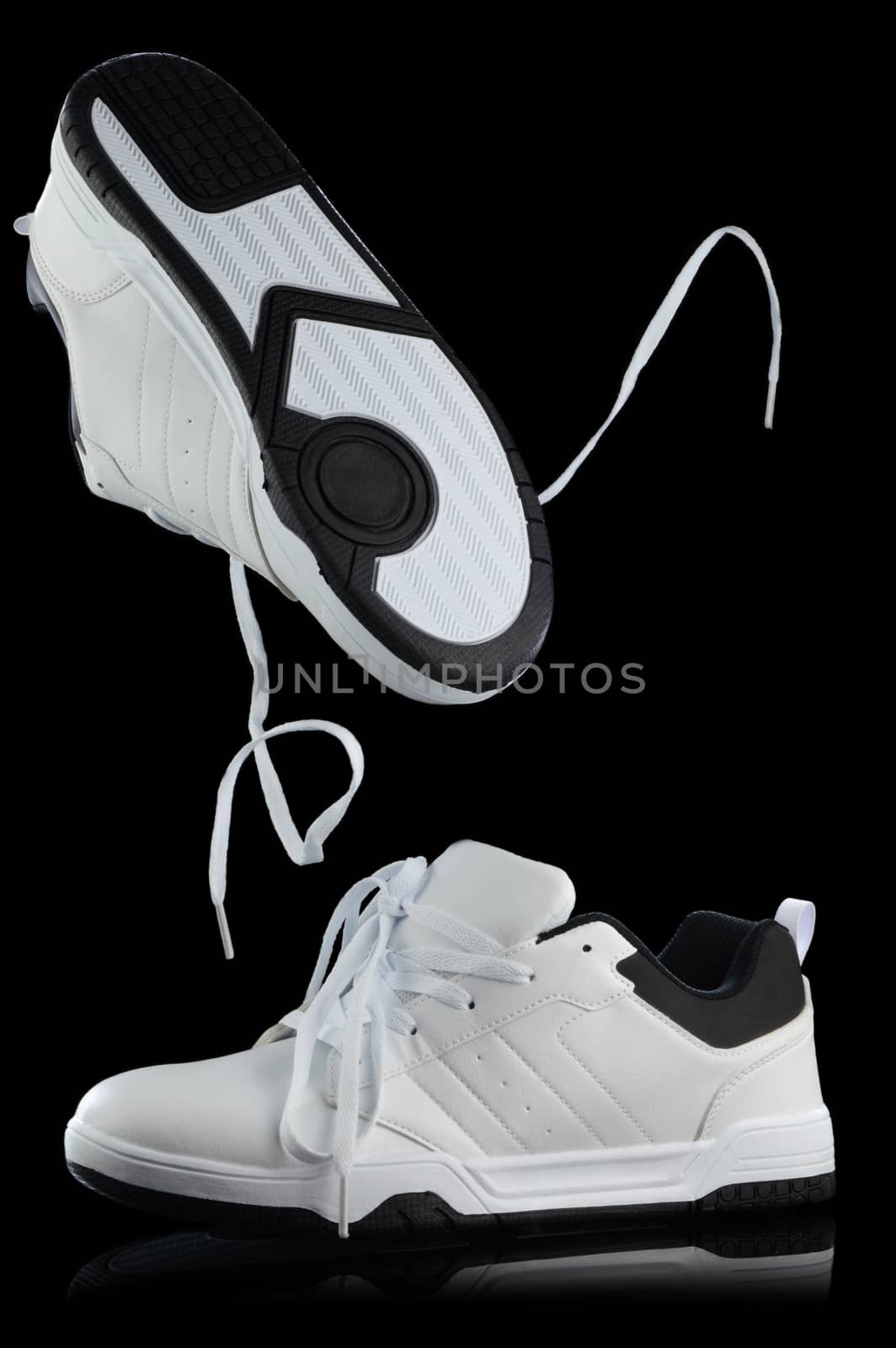 A stylish pair of mens white shoes captured over a black background making use of studio secrets to get the composition.