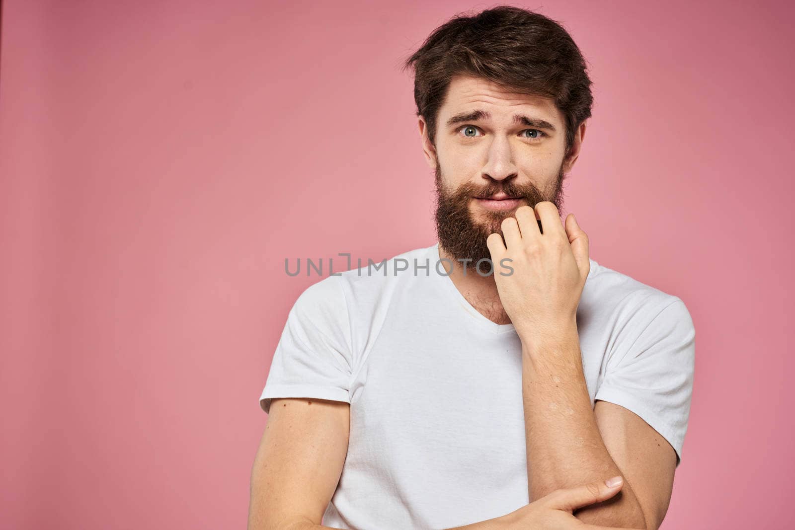 man in white t-shirt gesturing with his hands emotions fun pink background. High quality photo