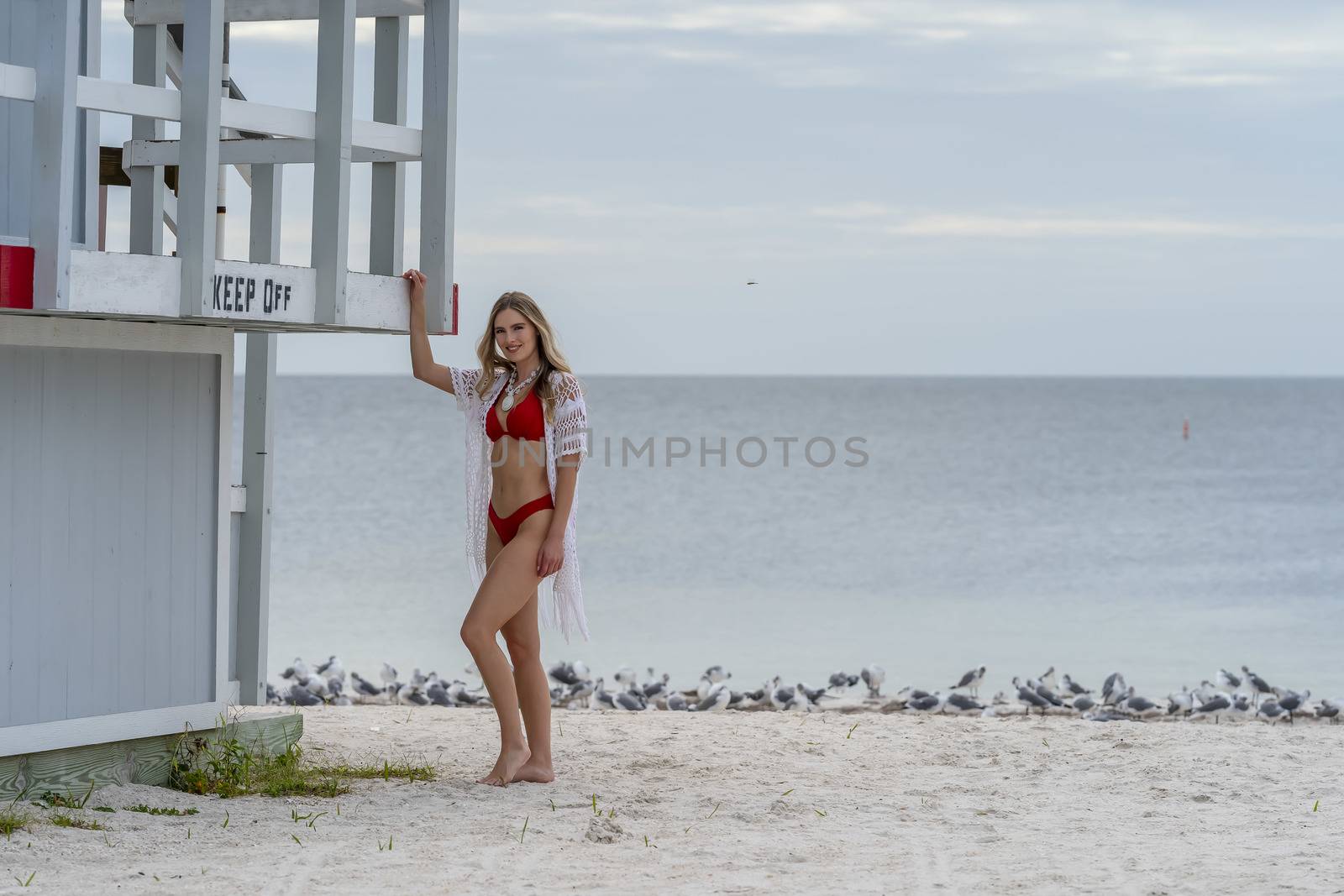 Lovely Blonde Bikini Model Posing Outdoors On A Caribbean Beach Near A Lifeguard Station by actionsports