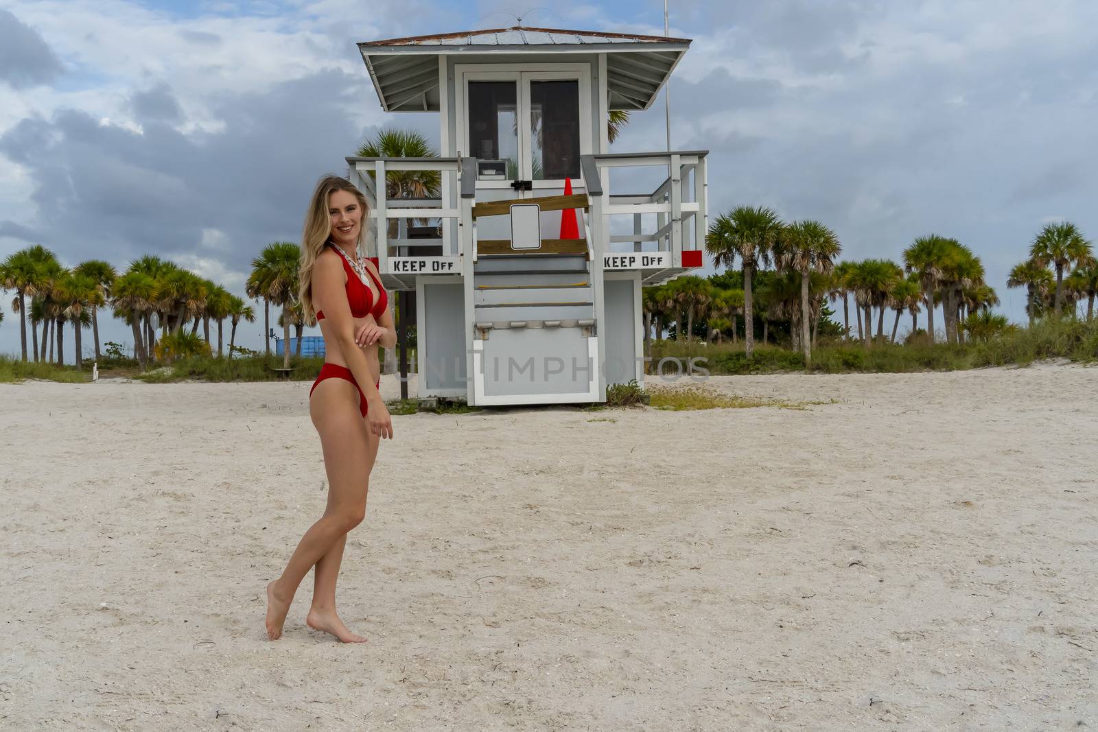 Lovely Blonde Bikini Model Posing Outdoors On A Caribbean Beach Near A Lifeguard Station by actionsports