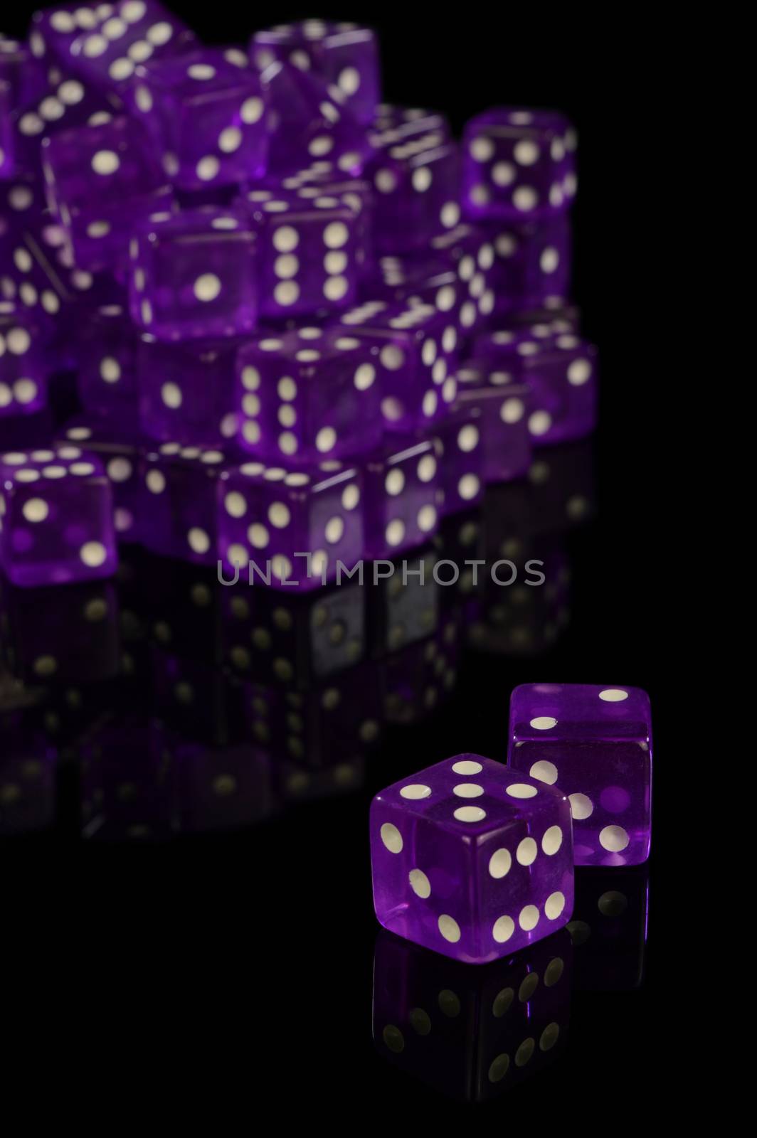 A pile of new unused Casino grade dice over a black reflective surface.