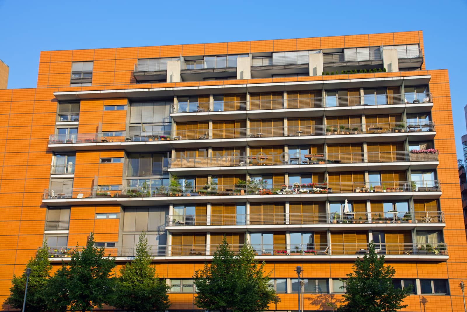 A modern orange building with rows of balconies