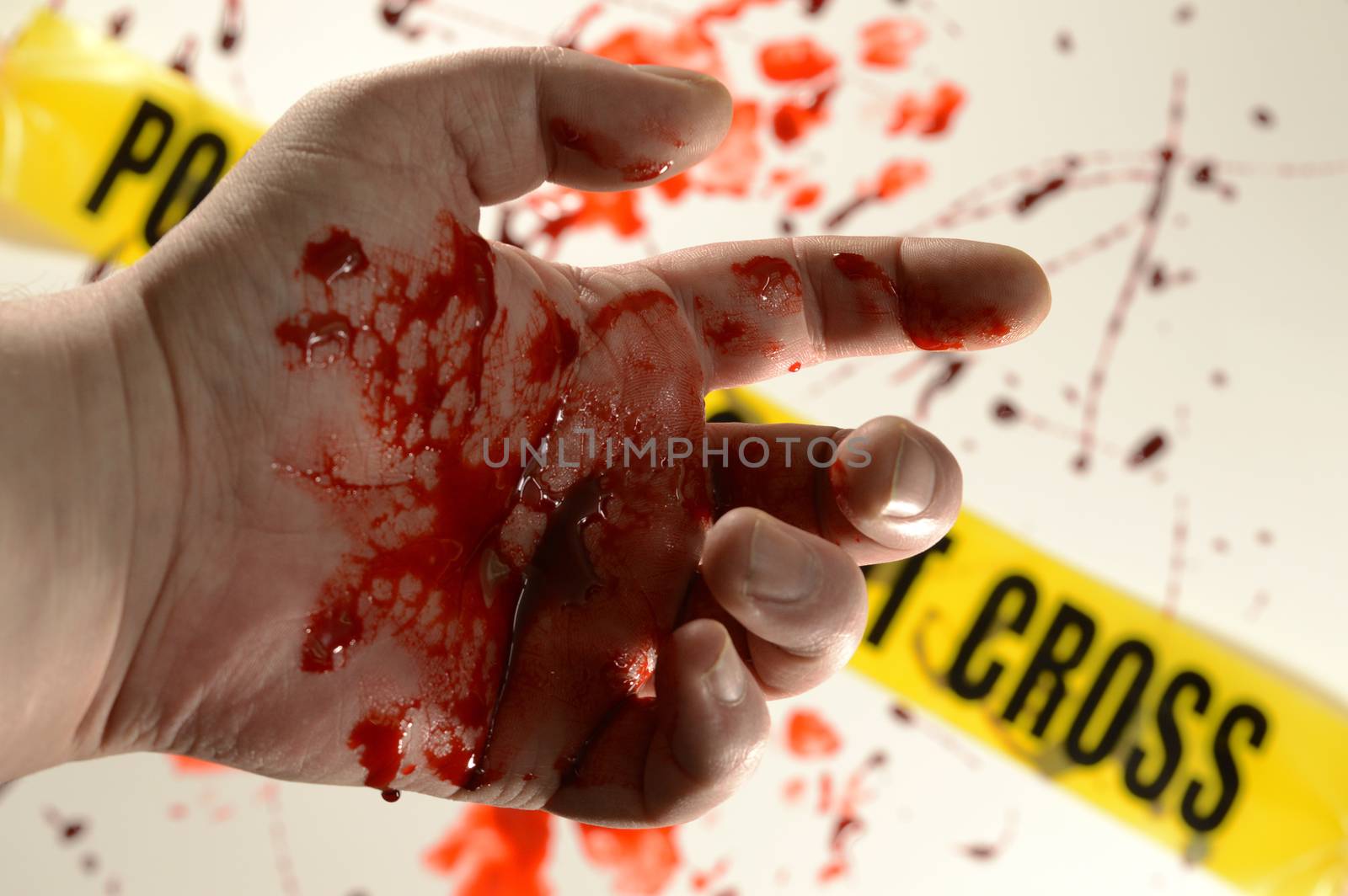 Closeup of a victim at a crime scene with bloody hands.