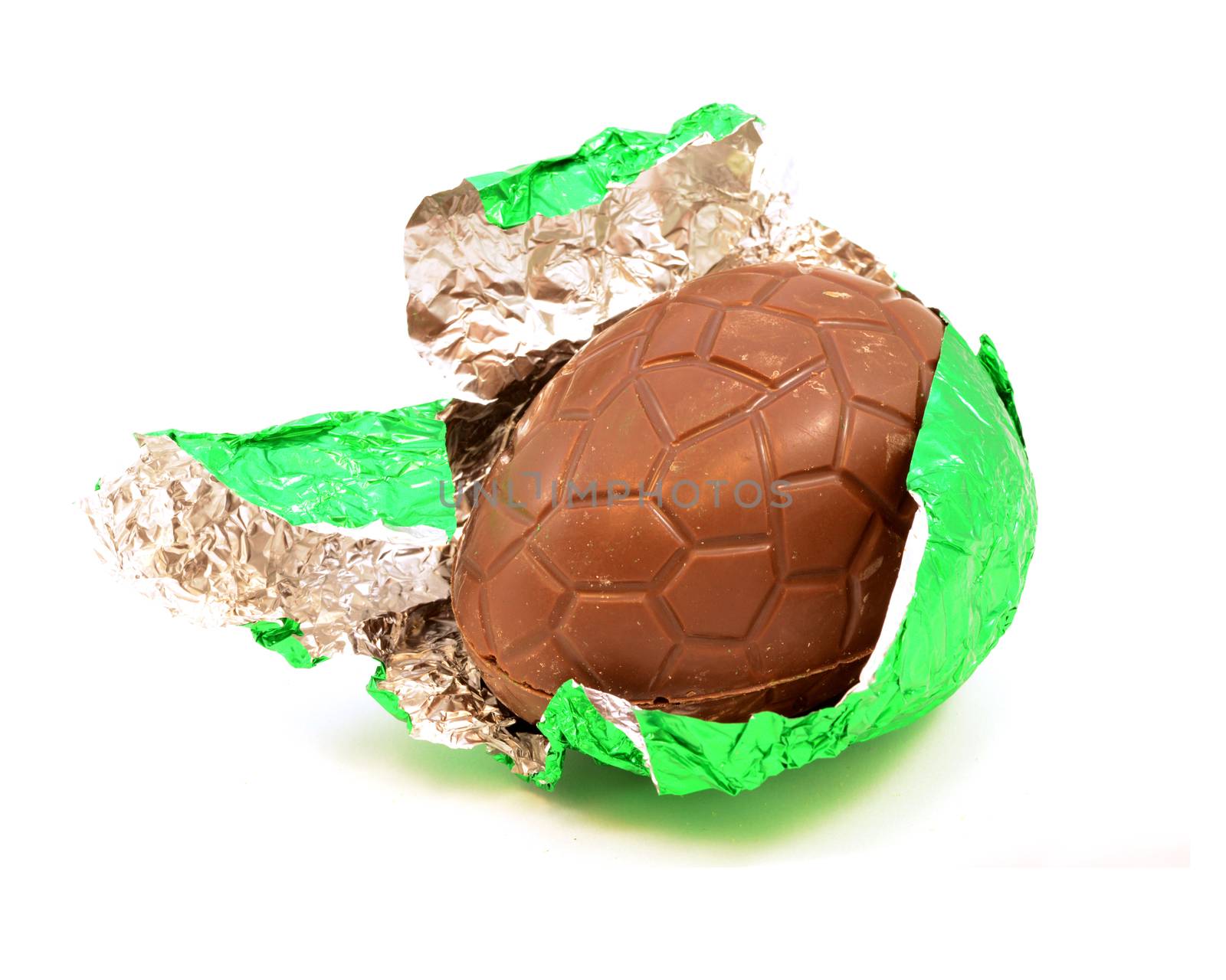 An isolated over white image of a hollow chocolate egg being unwrapped from its green foil.