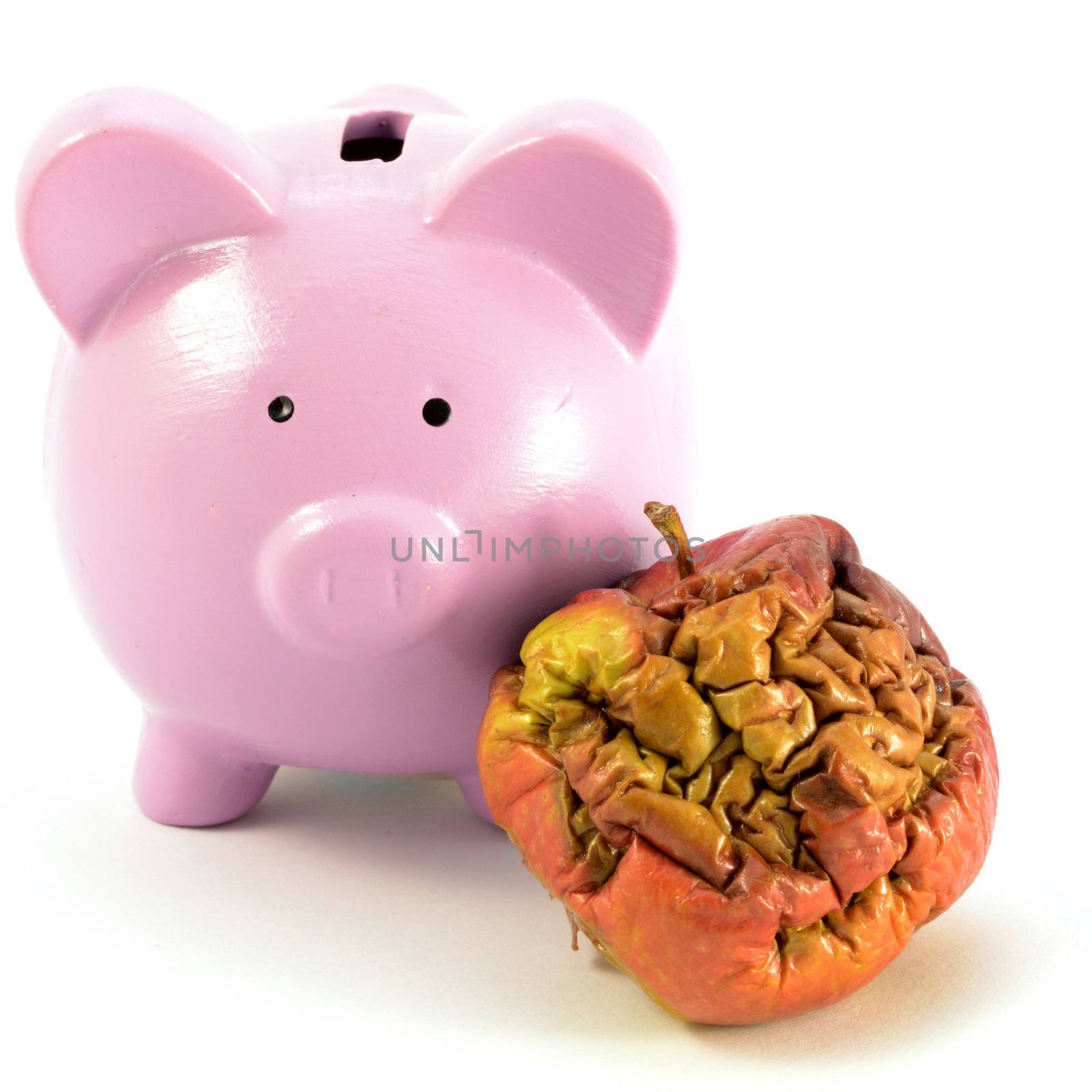 A conceptual image focusing on a pig bank and rotten apple for several monetary ideas.