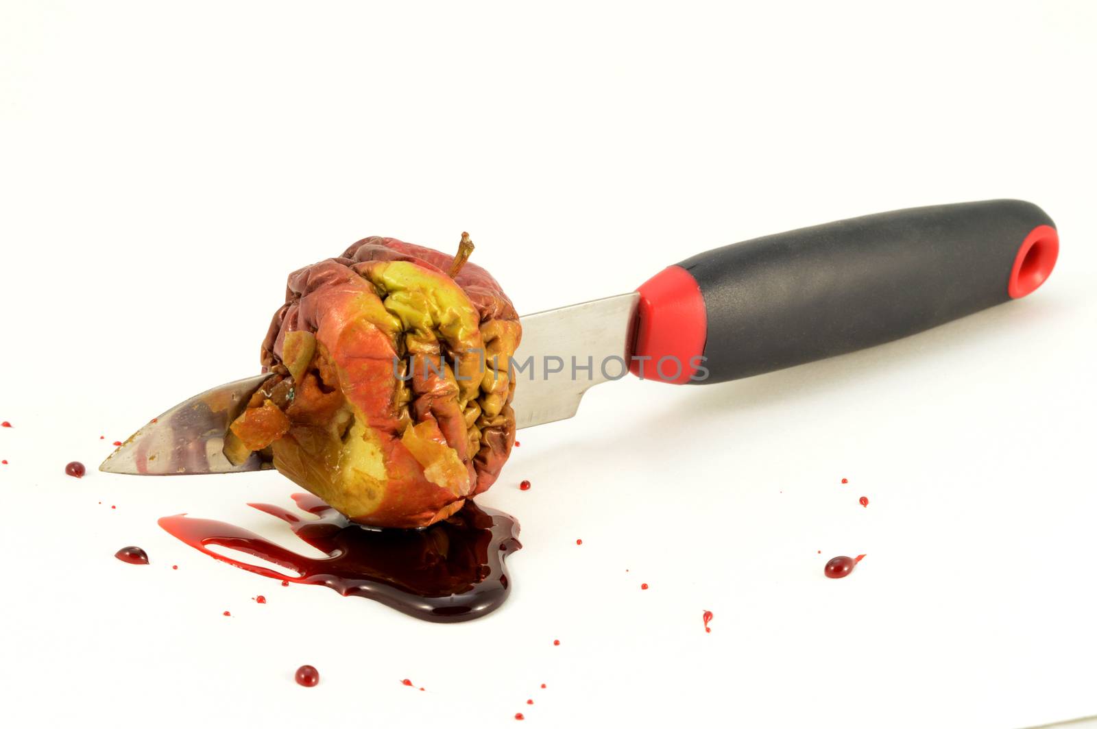 An isolated shot of one bad apple and a bloody knife wound.