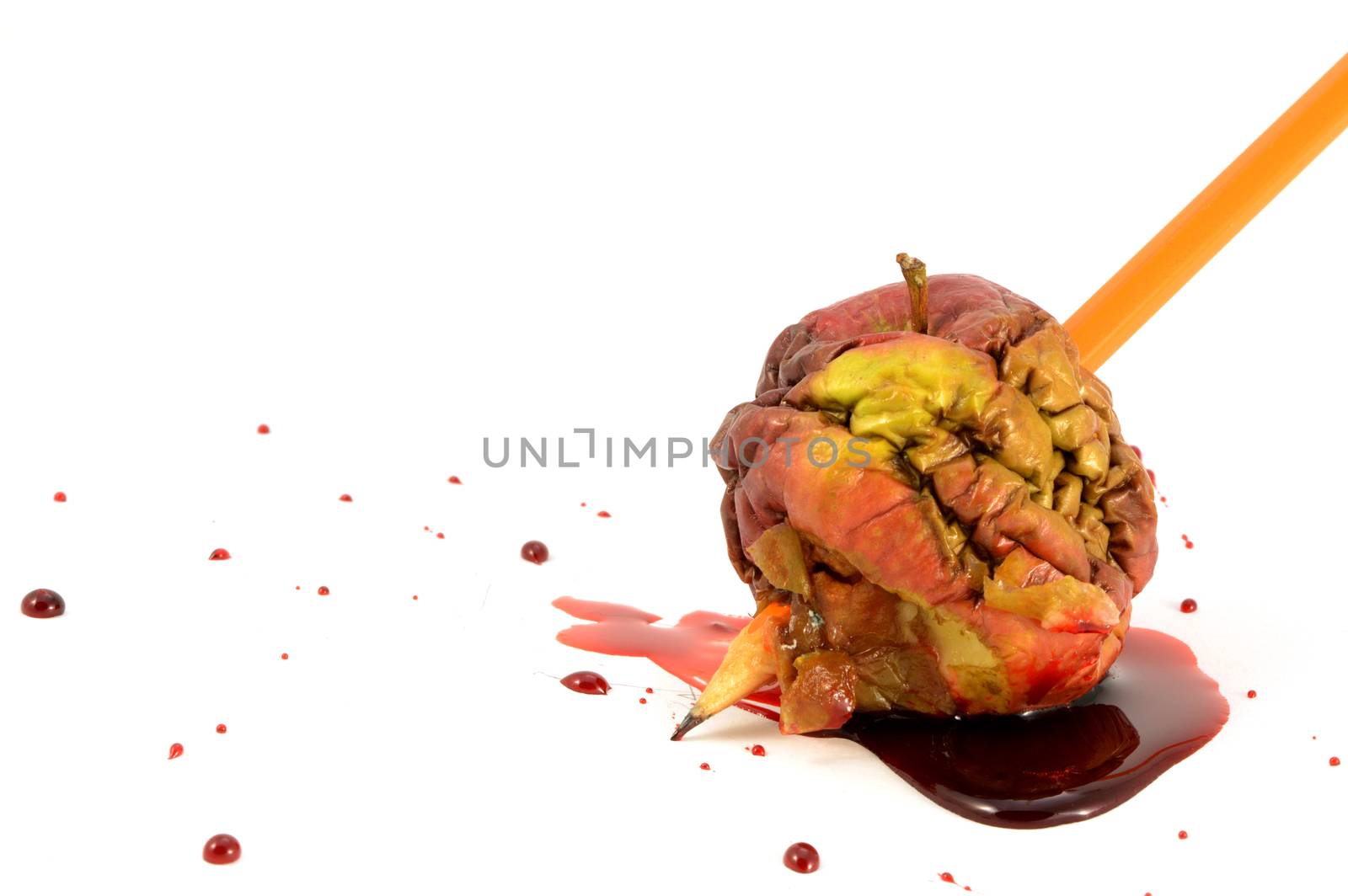 A closeup view of one bad apple being stabbed by a pencil with blood spilling.